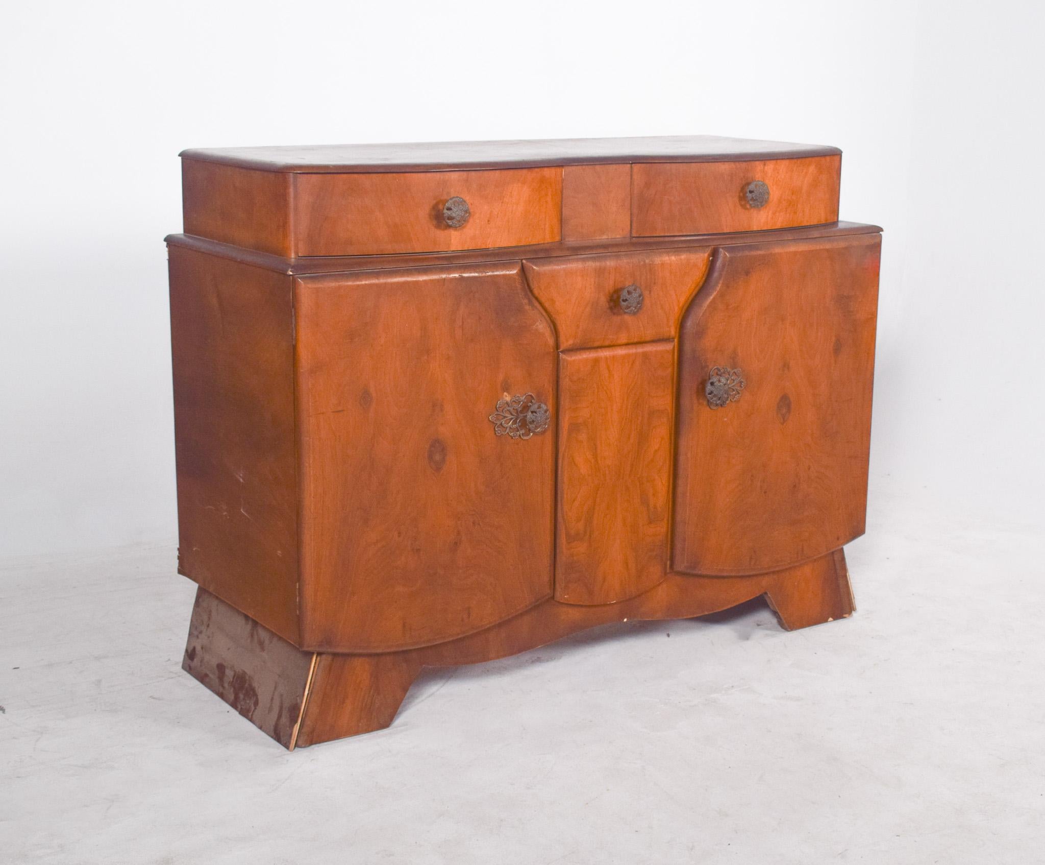 Art Deco Anrichte. Das mitteltönige, satinierte Holz wirkt warm und edel, und auf der Oberfläche ist eine reiche natürliche Maserung sichtbar.
Bestehend aus drei oberen Schubladen, von denen die mittlere schmaler ist, und drei Türen im unteren