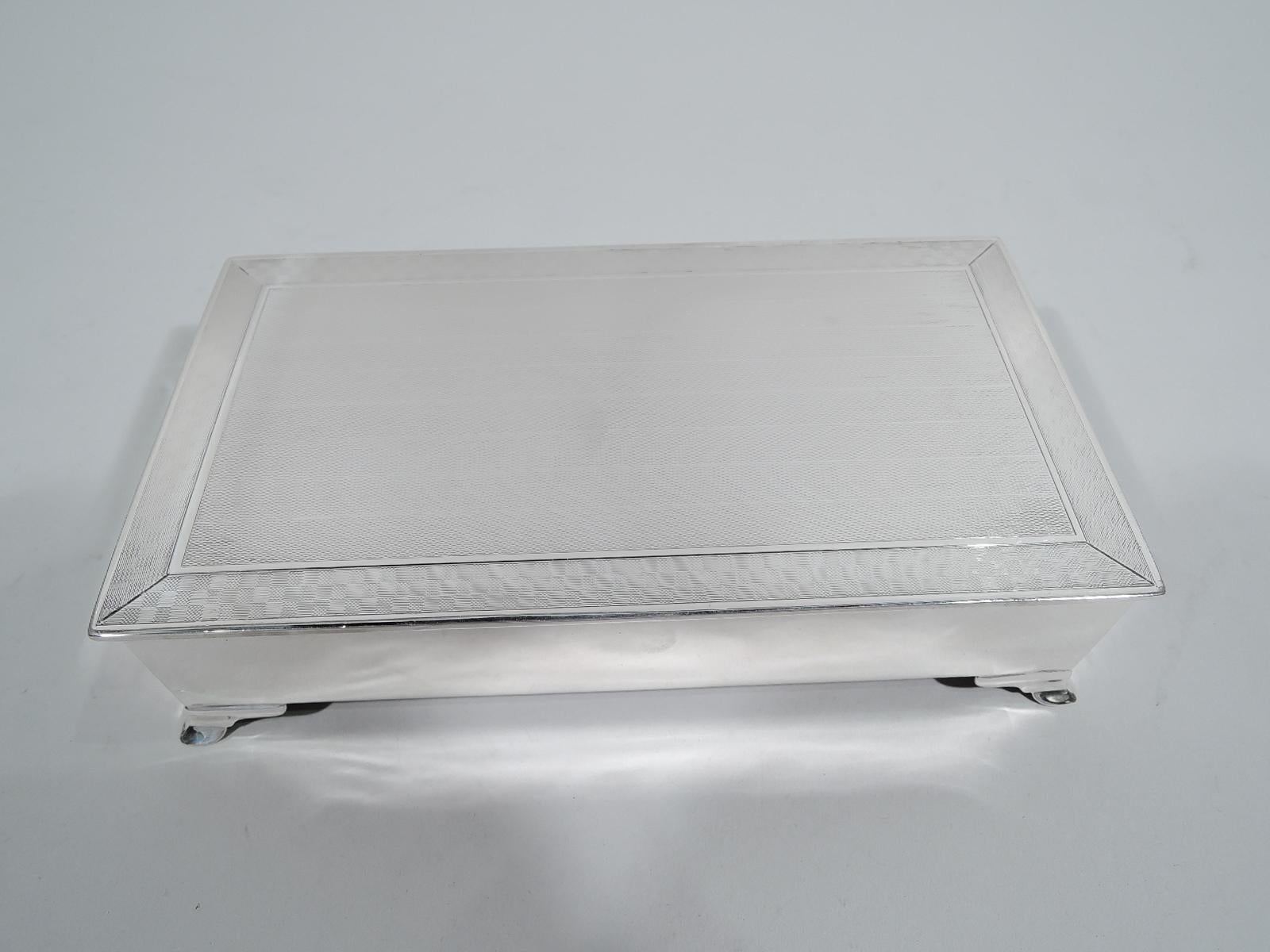 George V sterling silver box. Made by Henry Matthews in Birmingham in 1929. Rectangular with plain and straight sides, and corner bracket supports. Cover flat and hinged with slight overhang. Cover top has horizontal engine-turned wave ornament and