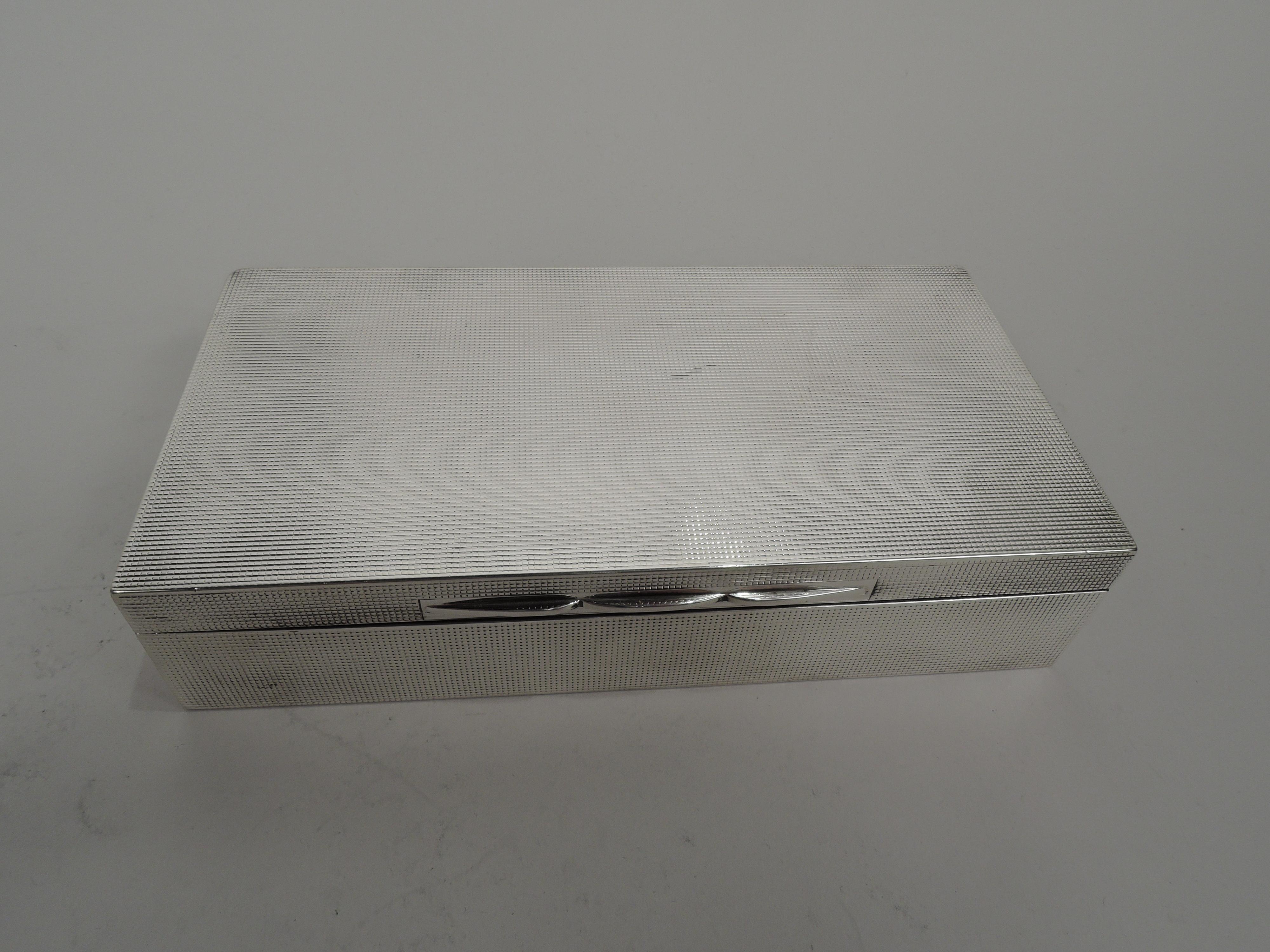 Edward VIII sterling silver box. Made by A. Wilcox in Birmingham in 1936. Rectangular with straight sides. Cover flat and hinged with triple tabs. Allover fine engine-turned grid ornament. Wood-lined interior. Open leather-lined underside. Fully