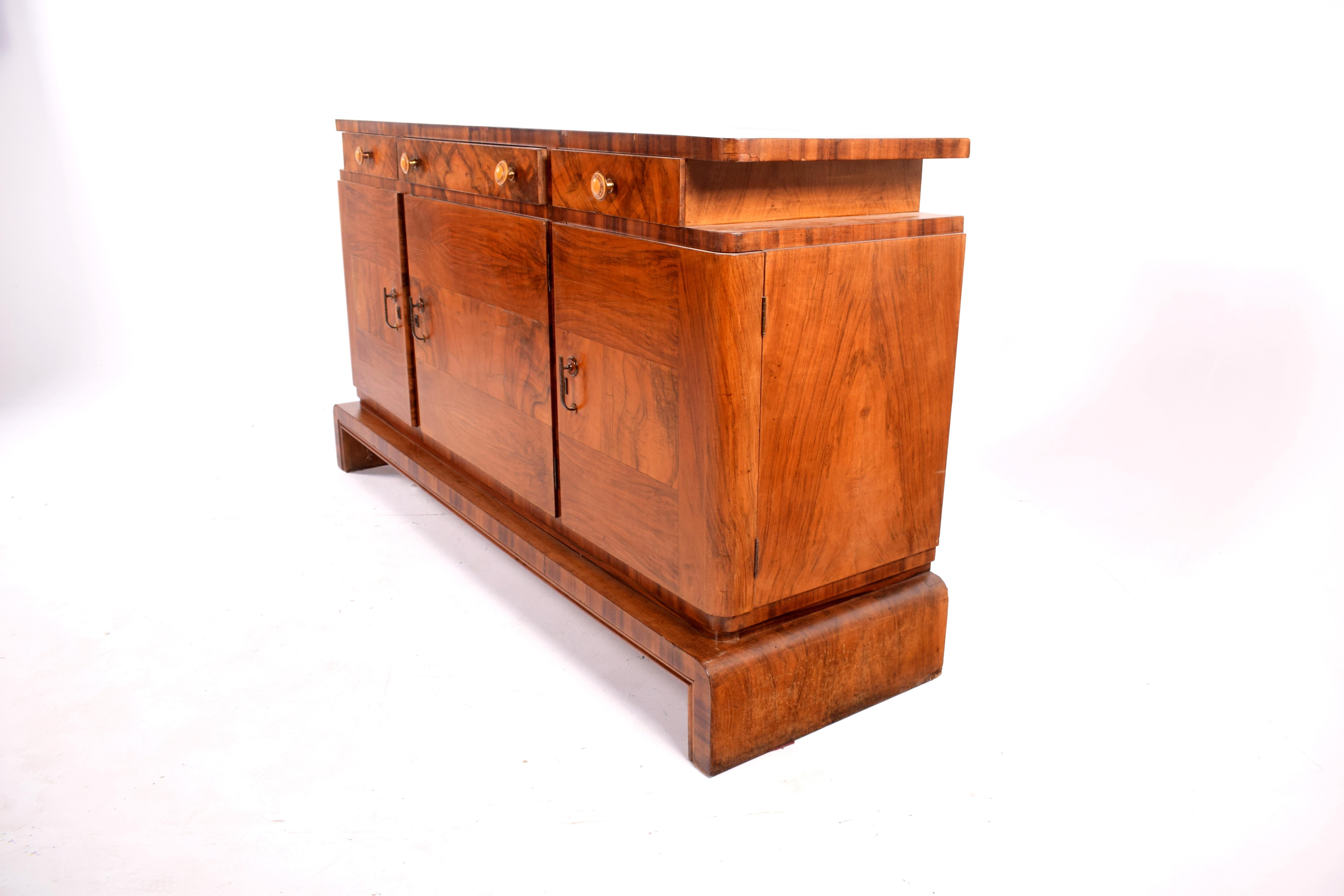 Art Deco walnut sideboard in good condition having been recently polished. The sideboard has a lift up top with 3 drawers and cupboard doors underneath with shelf.
