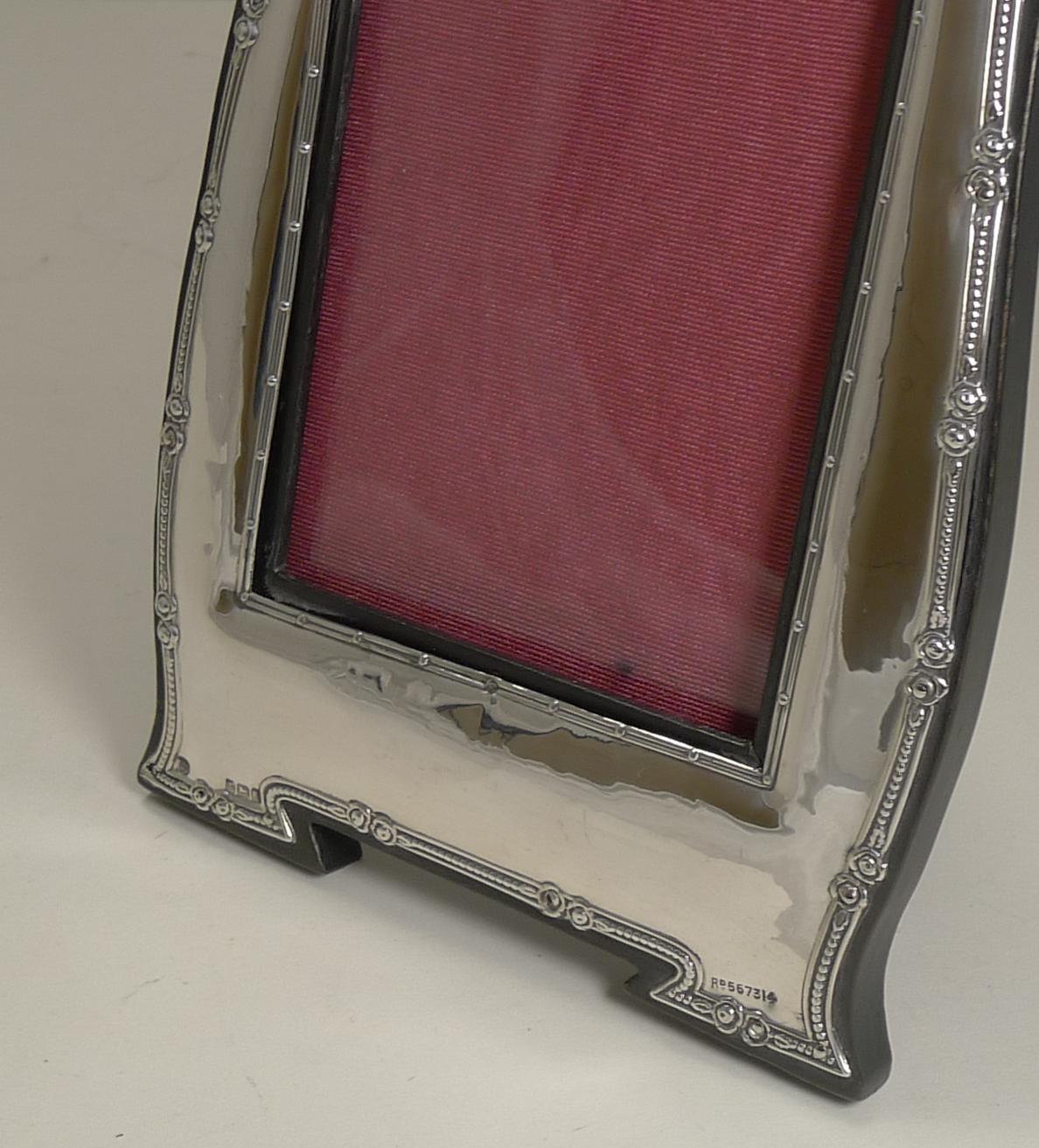 A very elegant photograph frame with an organic Art Nouveau shape outlined by a raised border.

The silver hallmark can be found on the left hand integral 