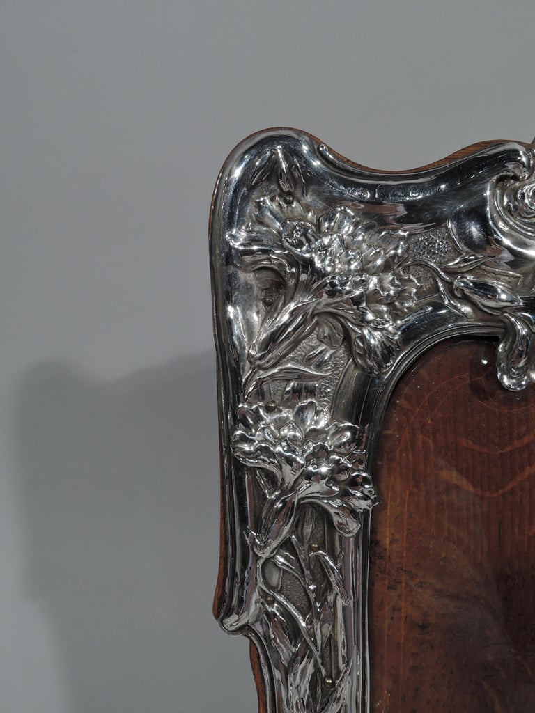 Art Nouveau sterling silver picture frame. Made by Henry Clifford Davis in Birmingham in 1904. Shaped rectangular window in shaped surround with bracket feet. Chased asymmetrical ornament: Climbing and entwined flowers spilling over molded border,