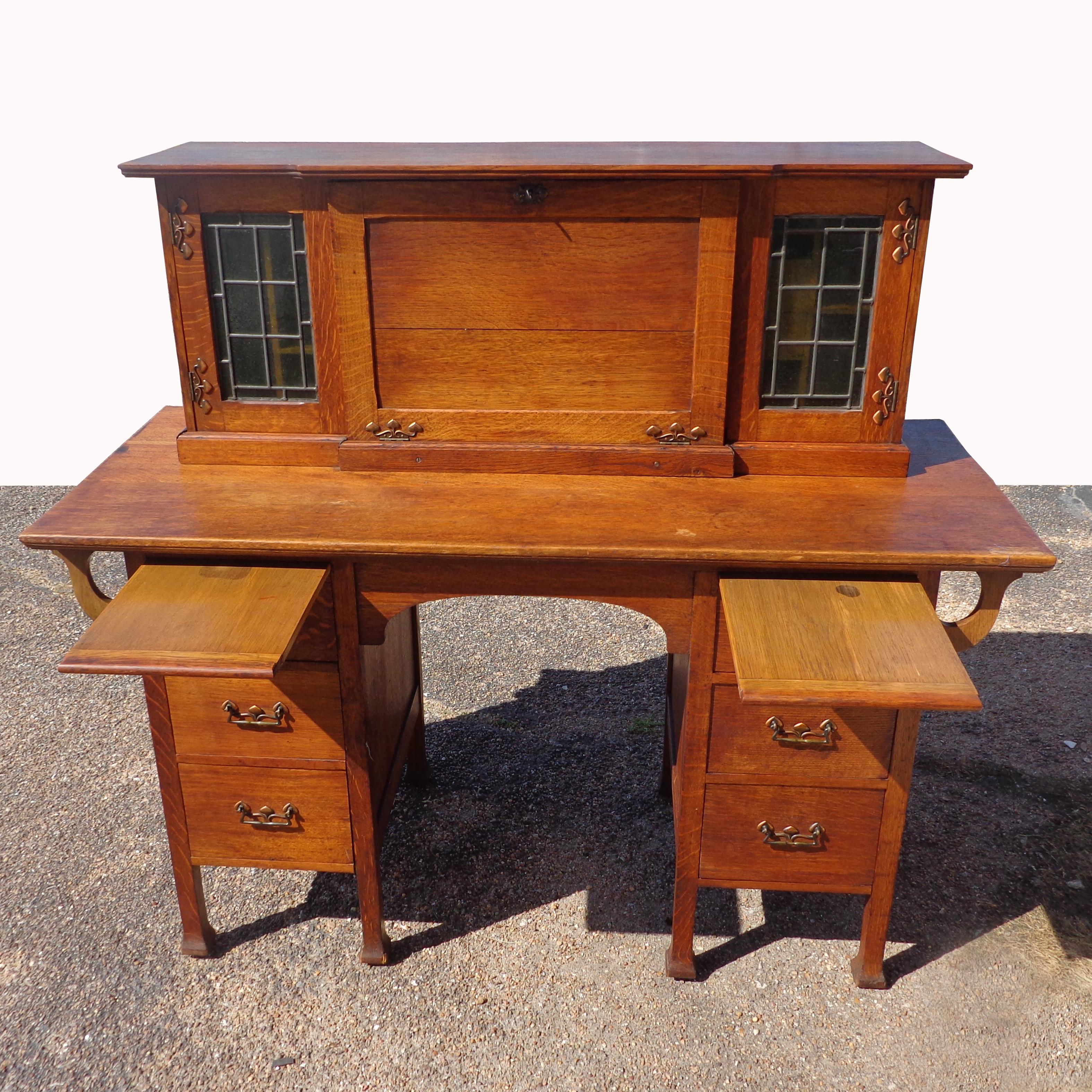 Antique English Arts & Crafts desk

 
Quarter sawn oak construction with Art Nouveau appliques and leaded glass doors frame the top organizer that folds down to a leather tooled work service. Six drawers and pull out tablets. Brass pulls and key
