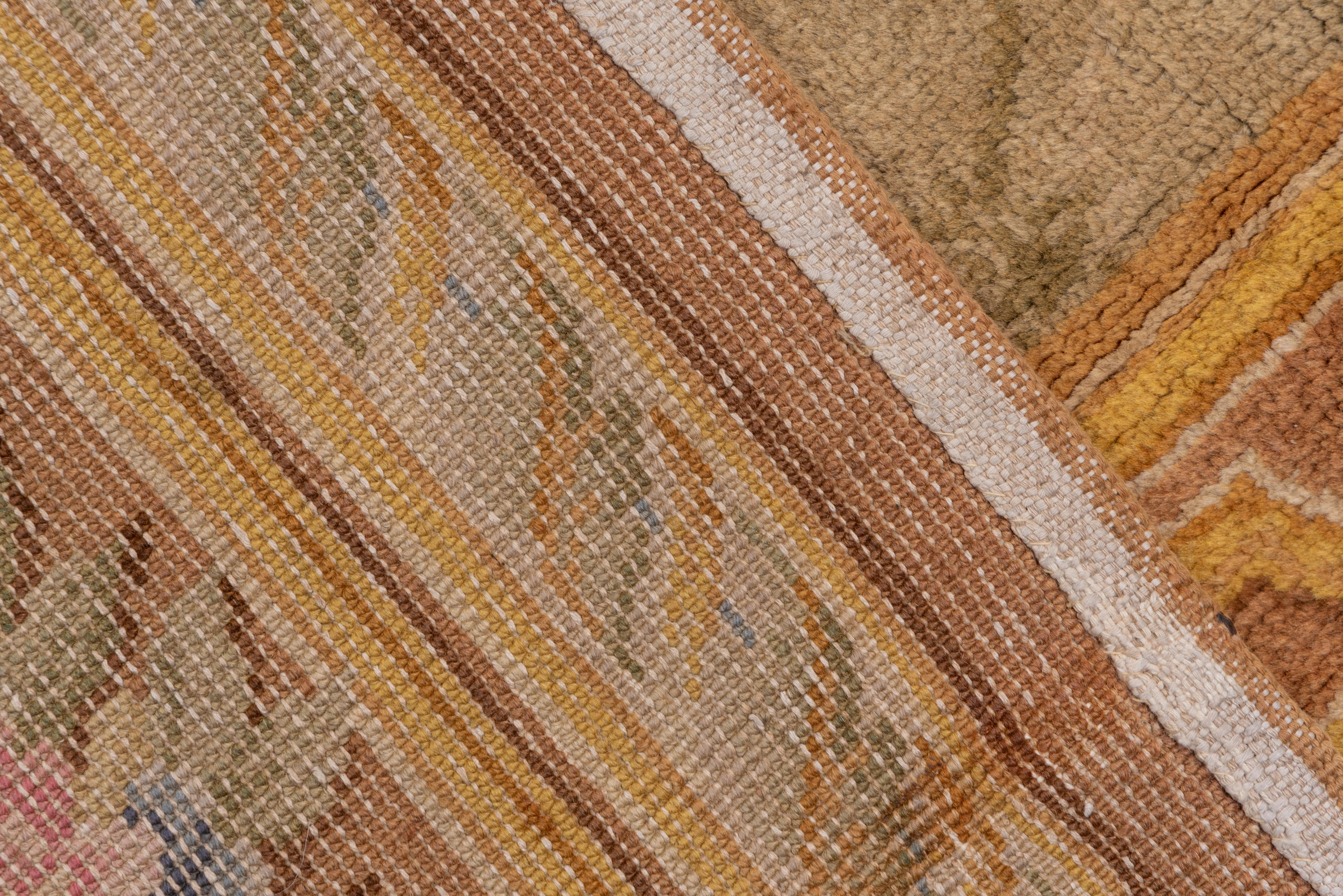 Ce tapis long, grossièrement tissé, présente un champ beige seafoam avec un motif ouvert de treillis de diamants, dans une bordure brune avec un travail de sangle en trompe l'oeil formant des cartouches enfermant des bouquets. Un tapis massif pour