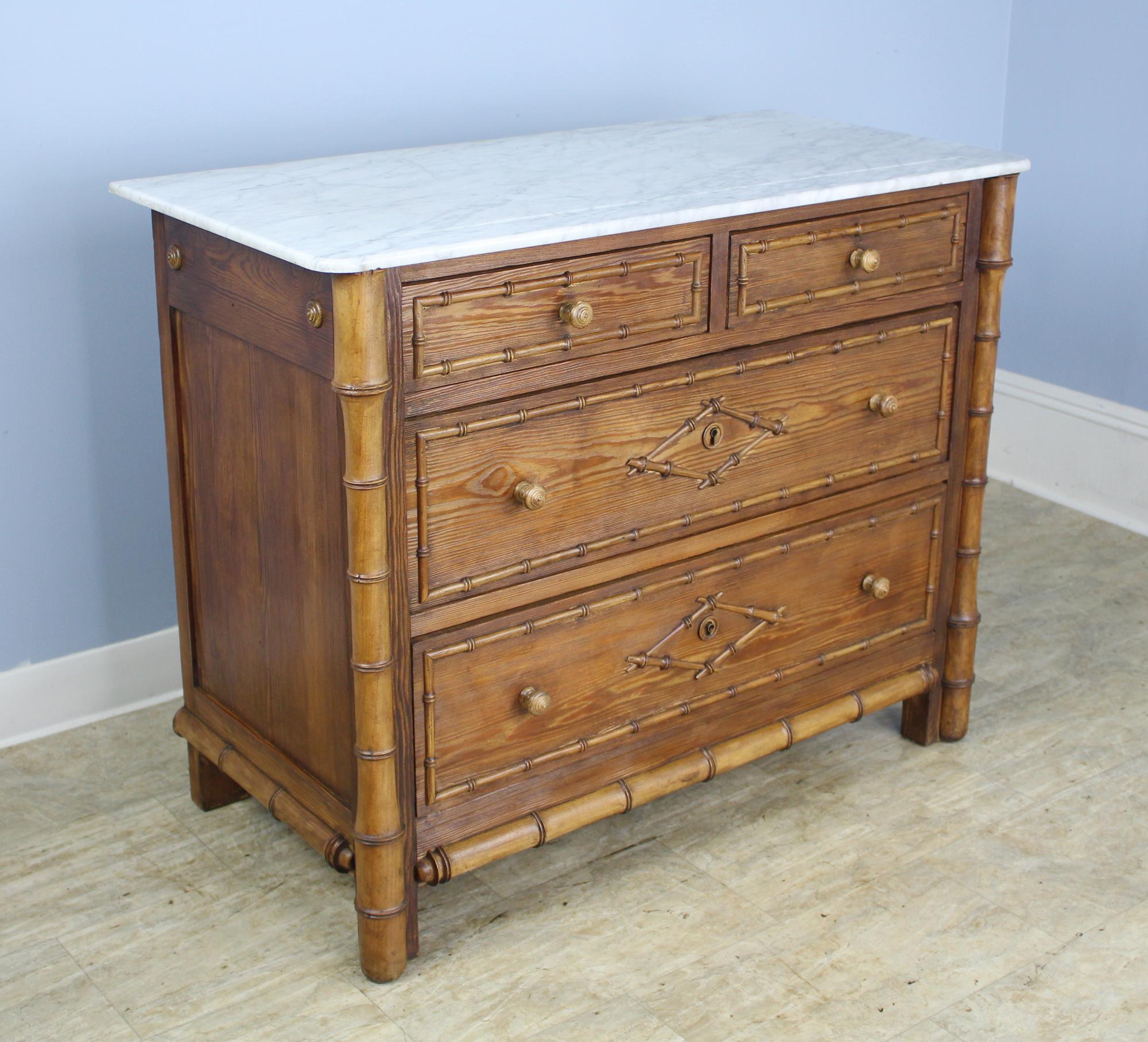 A charming chest of drawers with faux bamboo columns, mouldings and diamond motif drawer decorations. Classic two-over-two construction. The marble, which is original, is in good antique condition.