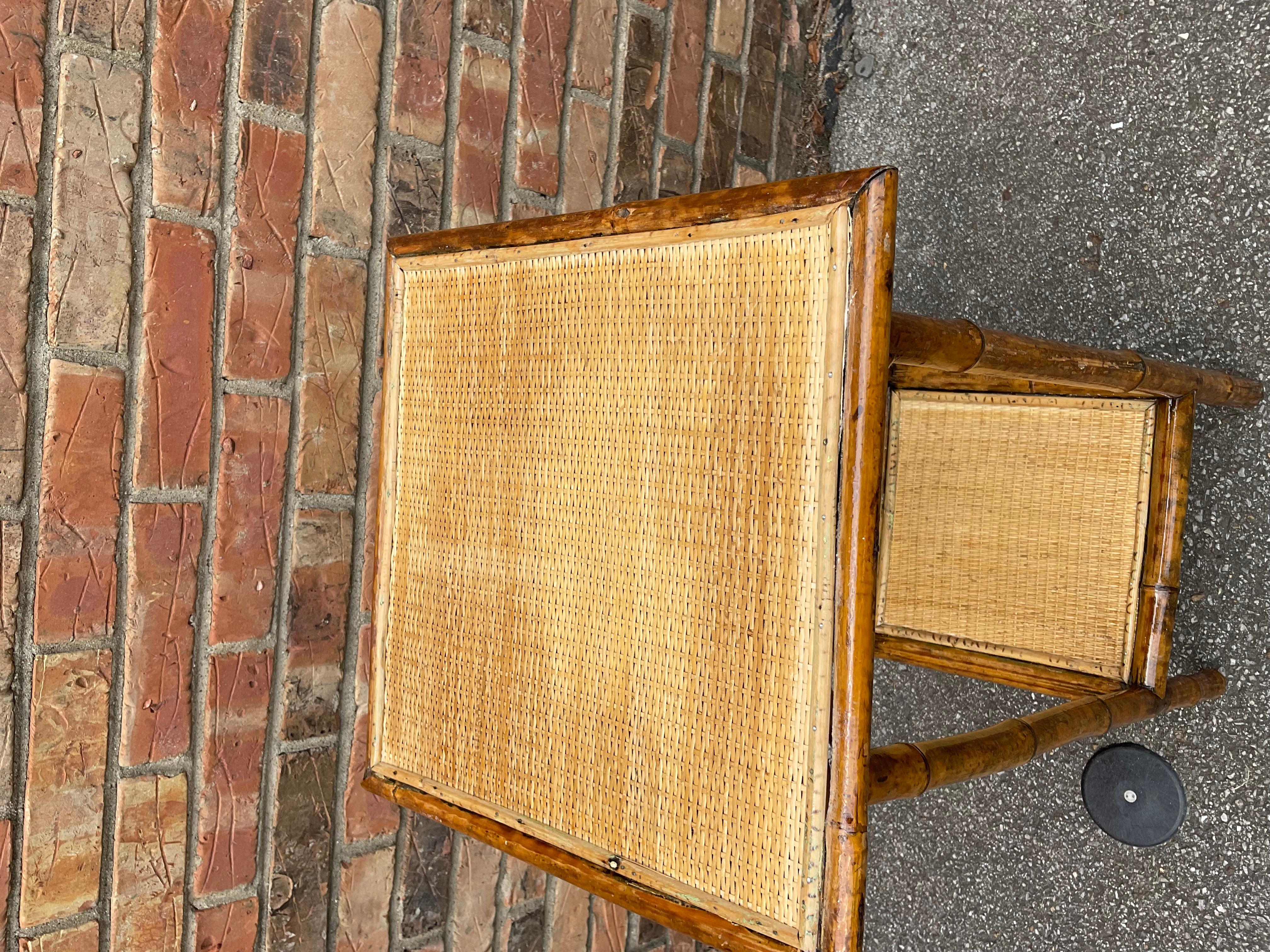 This is a beautiful 19th century English bamboo side table! Tables like these make excellent accent pieces because their color and style is so versatile. The dark hues of the burnt bamboo pair perfectly with the lighter golden of the rattan top and