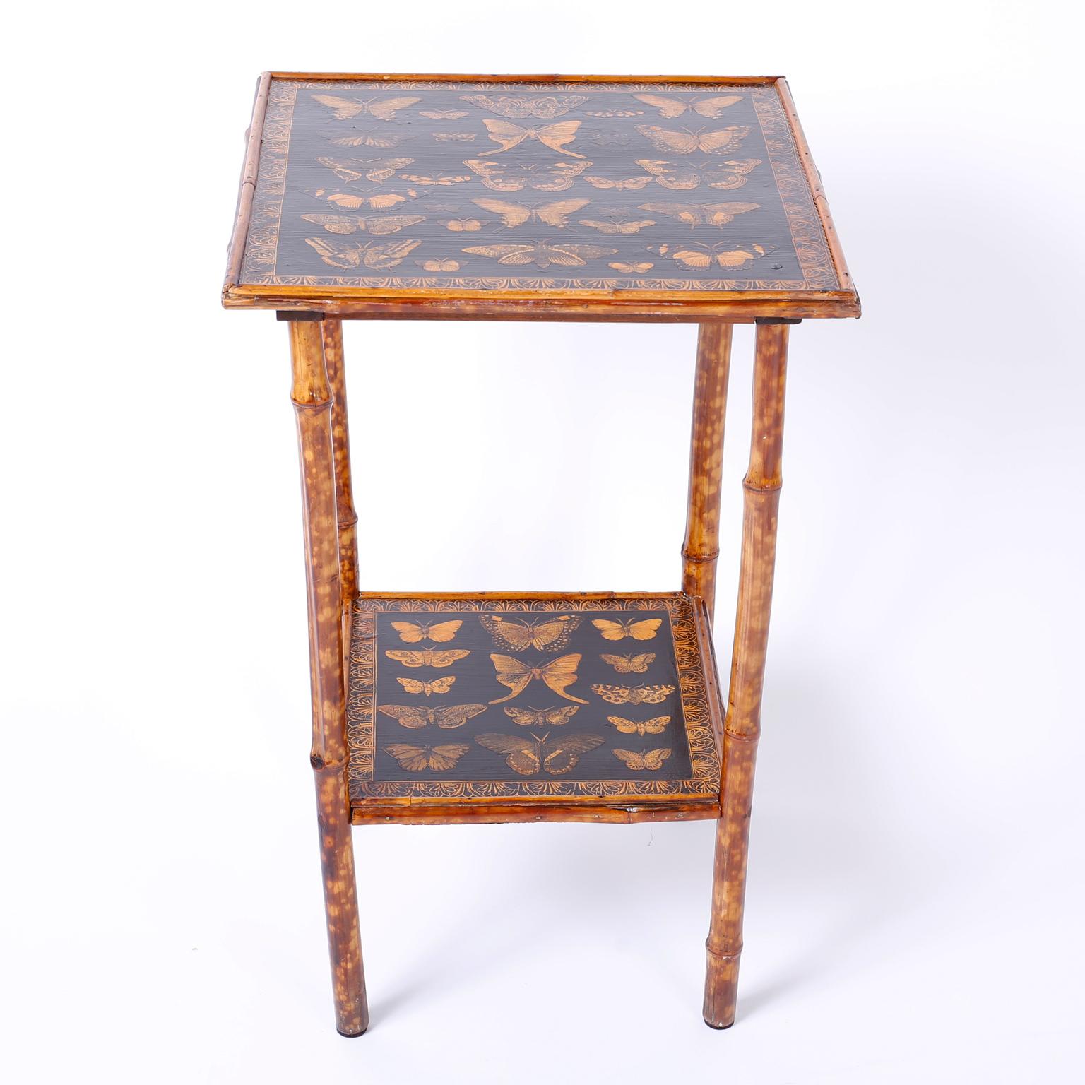 Antique English square bamboo occasional table ingeniously decorated with contemporary decoupage butterflies on both tiers.