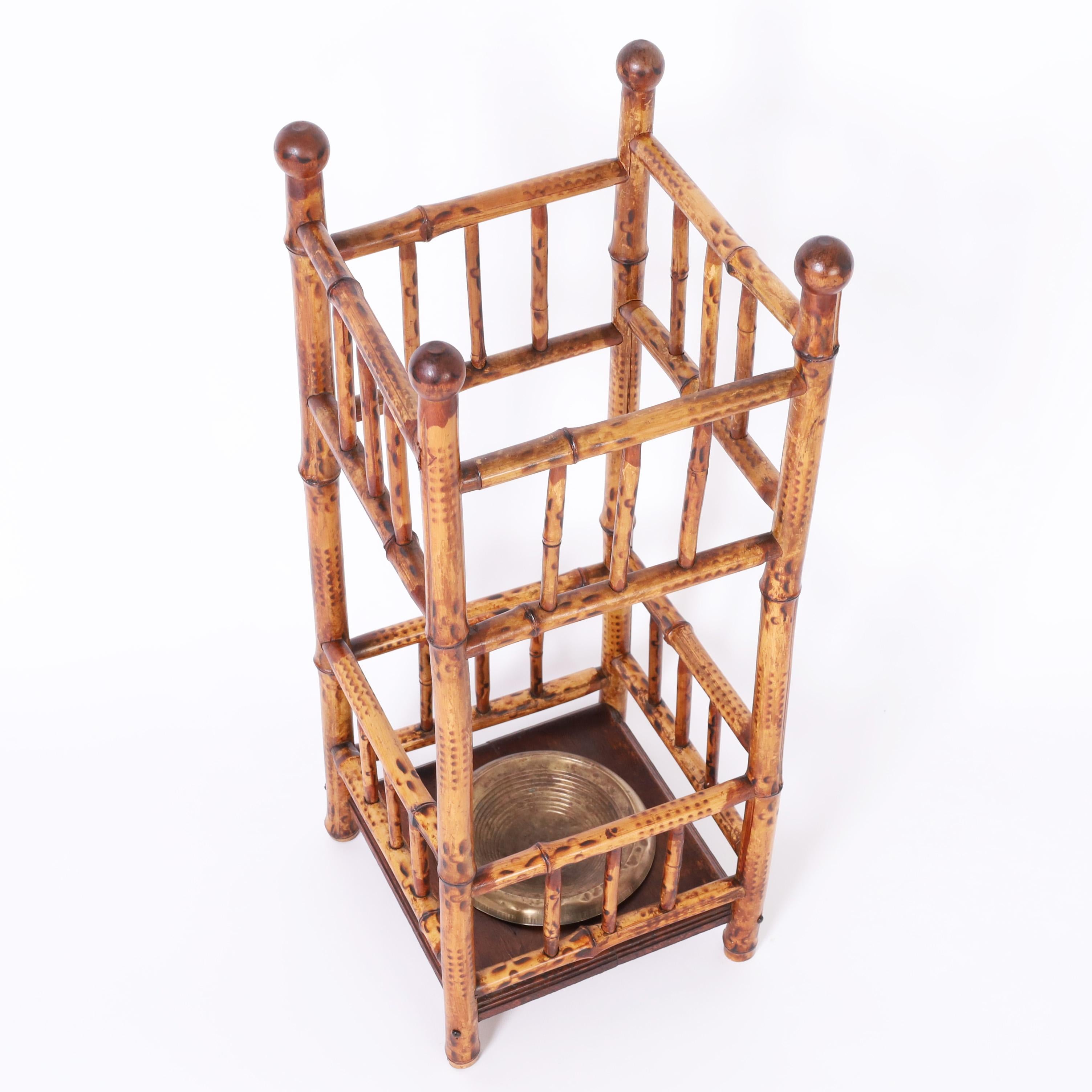 English 19th century umbrella stand handcrafted in burnt bamboo with ball finials, stretchers and balustrades, and a turned brass tray in a wood base.