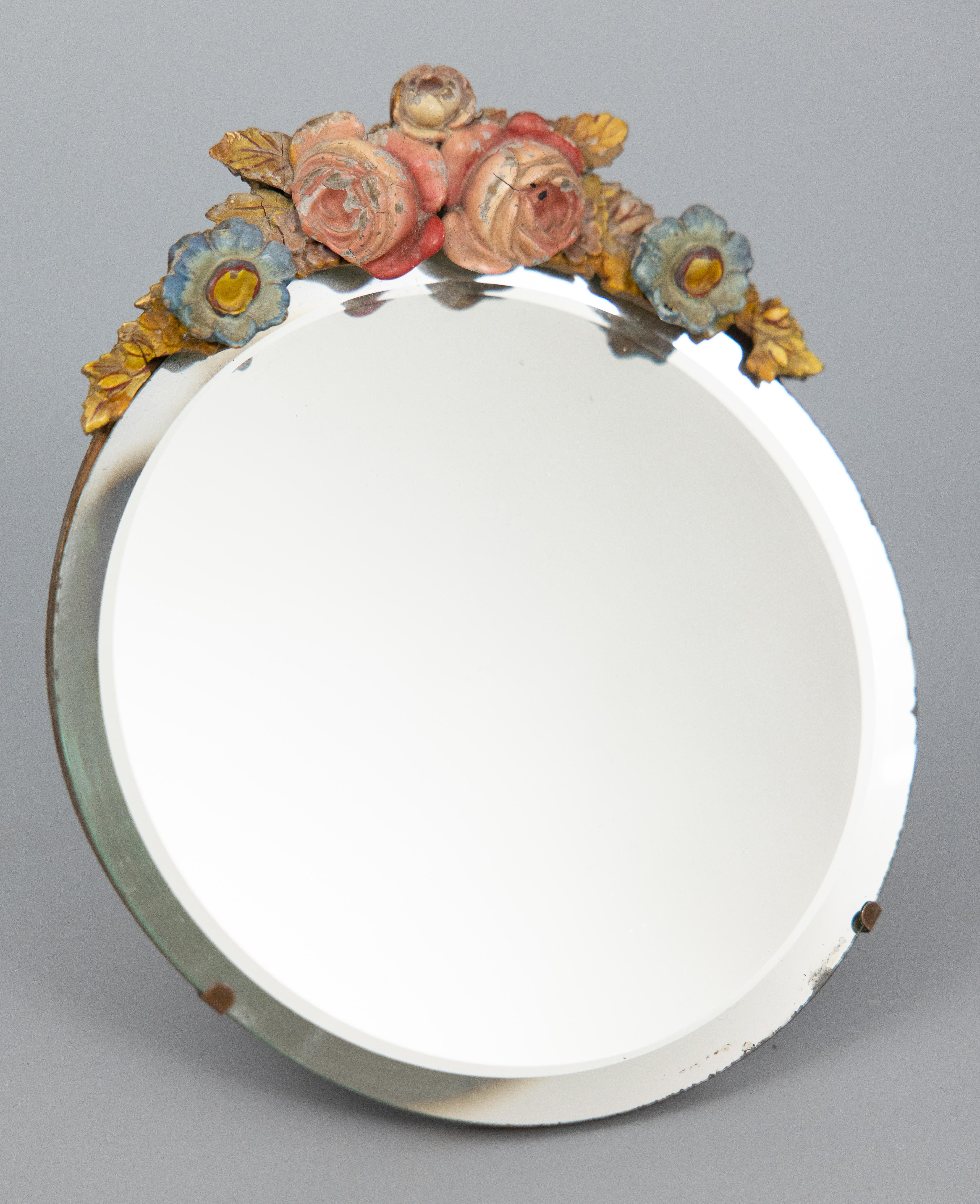 A fine antique English barbola dressing table or vanity oval mirror with easel, circa 1920. This beautiful mirror has beveled glass and is crowned with a gesso floral swag. It would be lovely displayed on a dresser, vanity, or small desk.