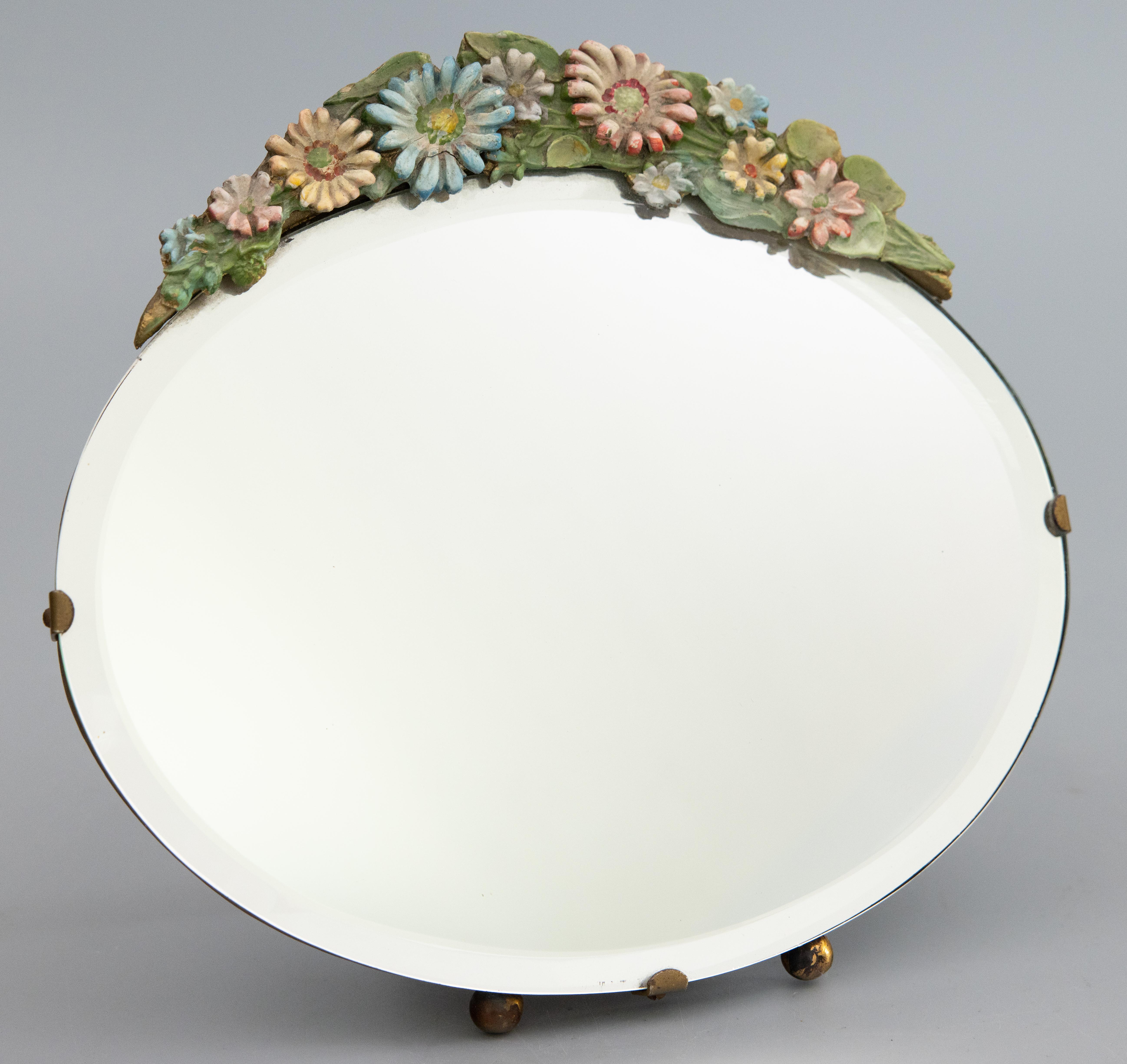 A fine antique English barbola dressing table or vanity oval mirror with easel, circa 1920. This beautiful mirror has beveled glass and is crowned with a gesso floral swag. It would be lovely displayed on a dresser, vanity, or small
