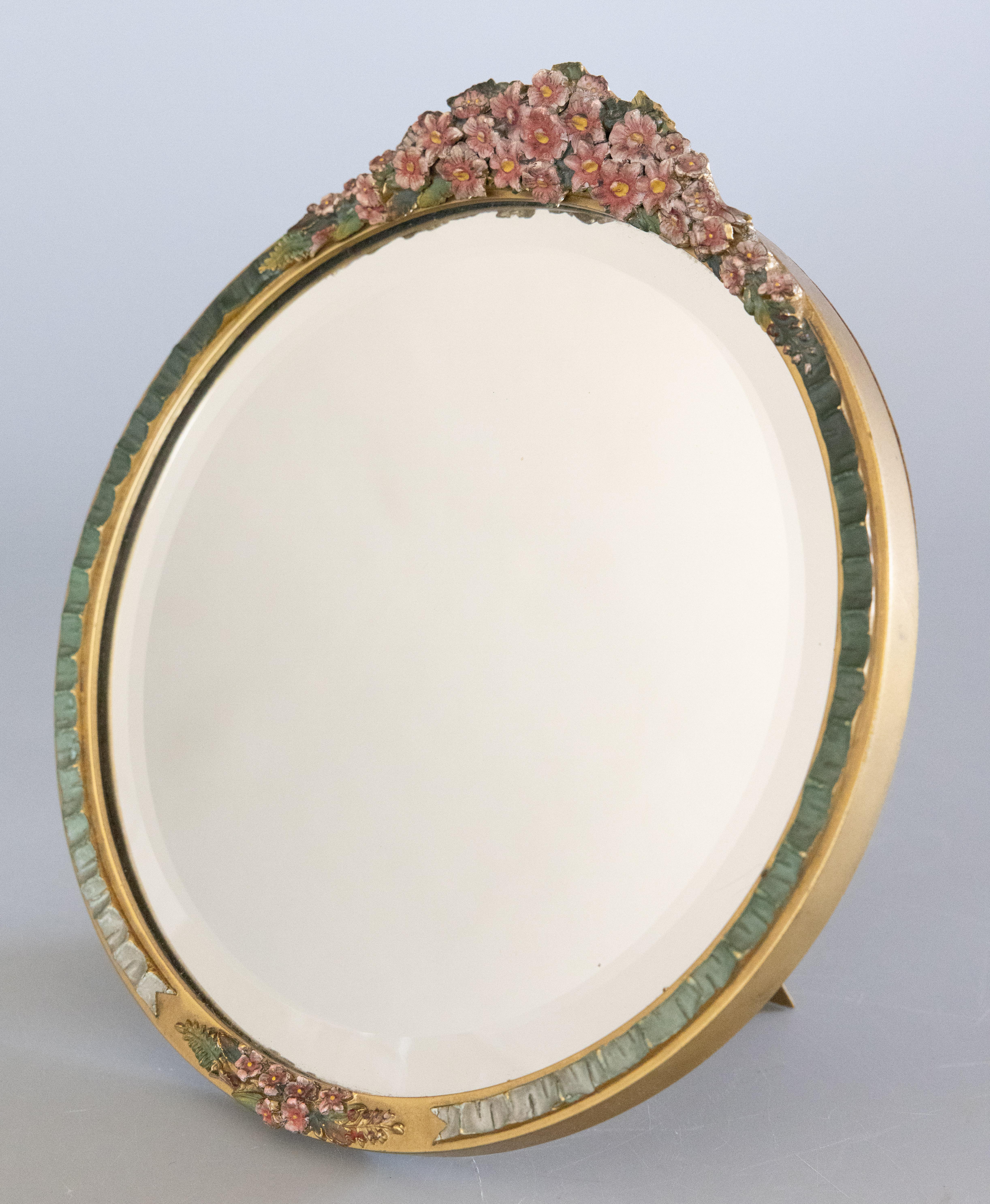 A fine antique English barbola round dressing table or vanity mirror with an easel back, circa 1920. This beautiful mirror features a beveled mirror glass surrounded by a ruched design border hand painted with gorgeous colors, gilt accents, and