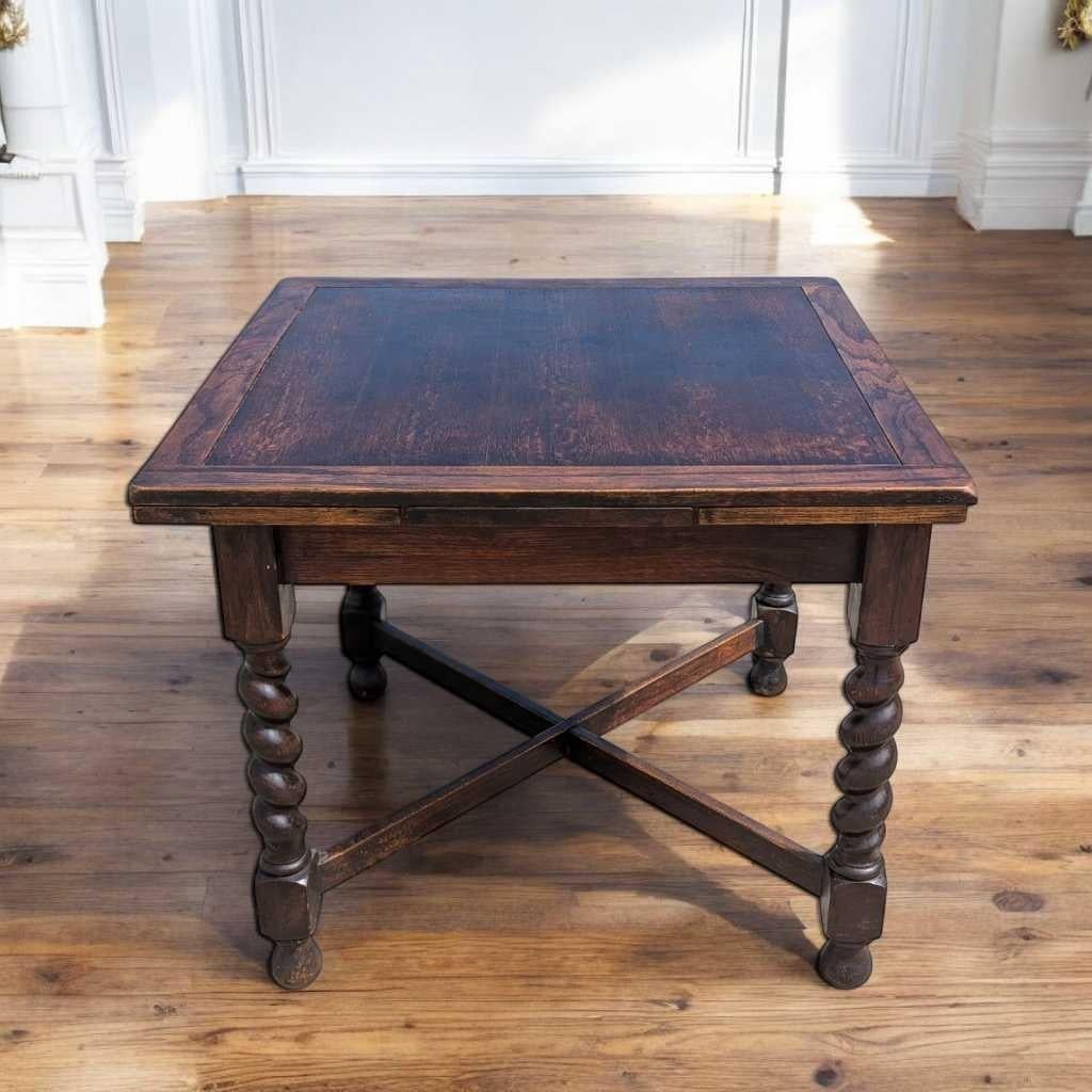 A distinctive draw-leaf dining table in the Edwardian-era English tradition, crafted from solid oak and showcasing iconic barley twist legs with a stretcher base. This piece blends timeless antique design with enduring craftsmanship—ideal for