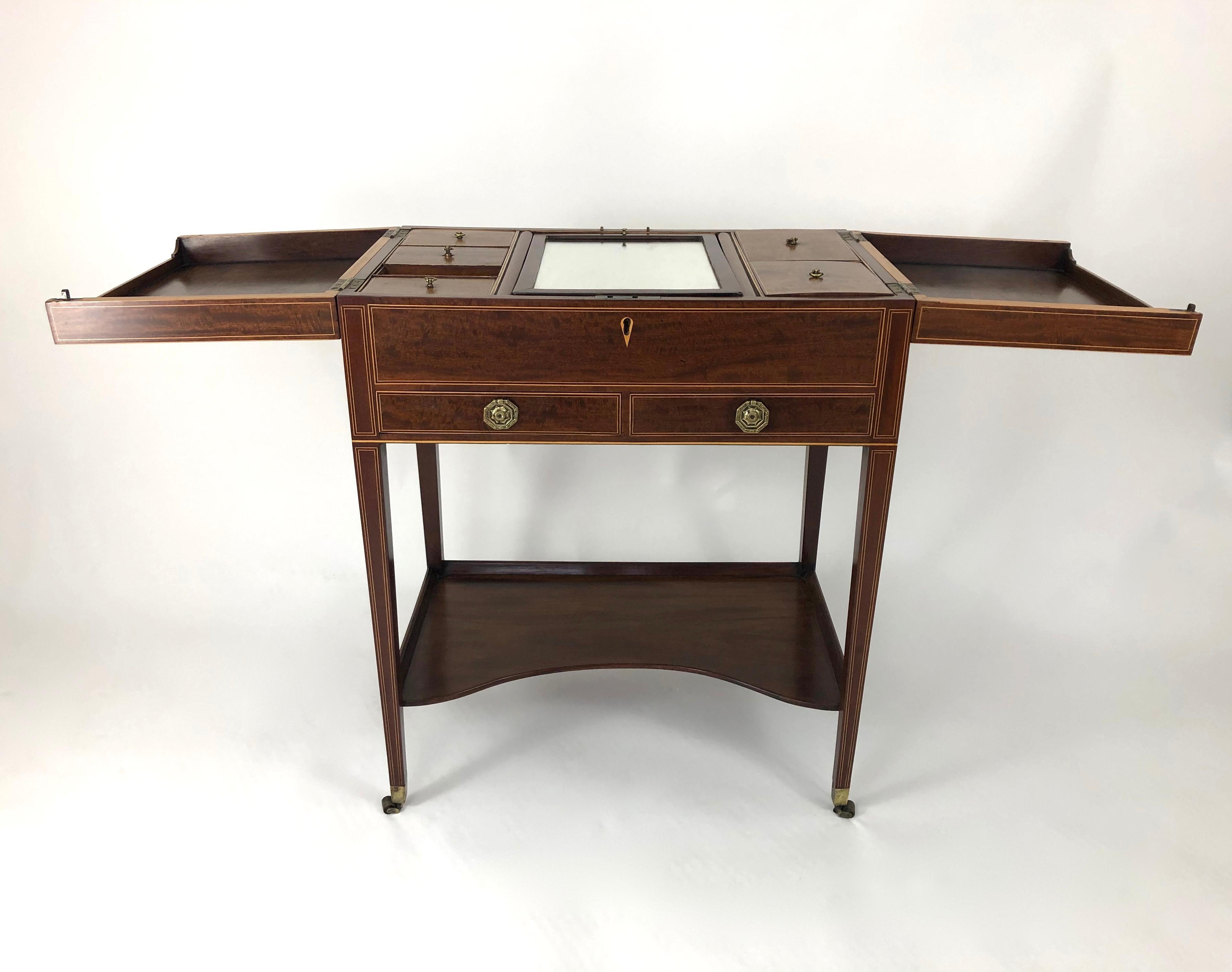 A fine quality antique English dressing table, circa 1800, often referred to as a Beau Brummell, in richly colored and figured inlaid mahogany. The top opens up to reveal an adjustable folding mirror and storage space flanked by covered compartments