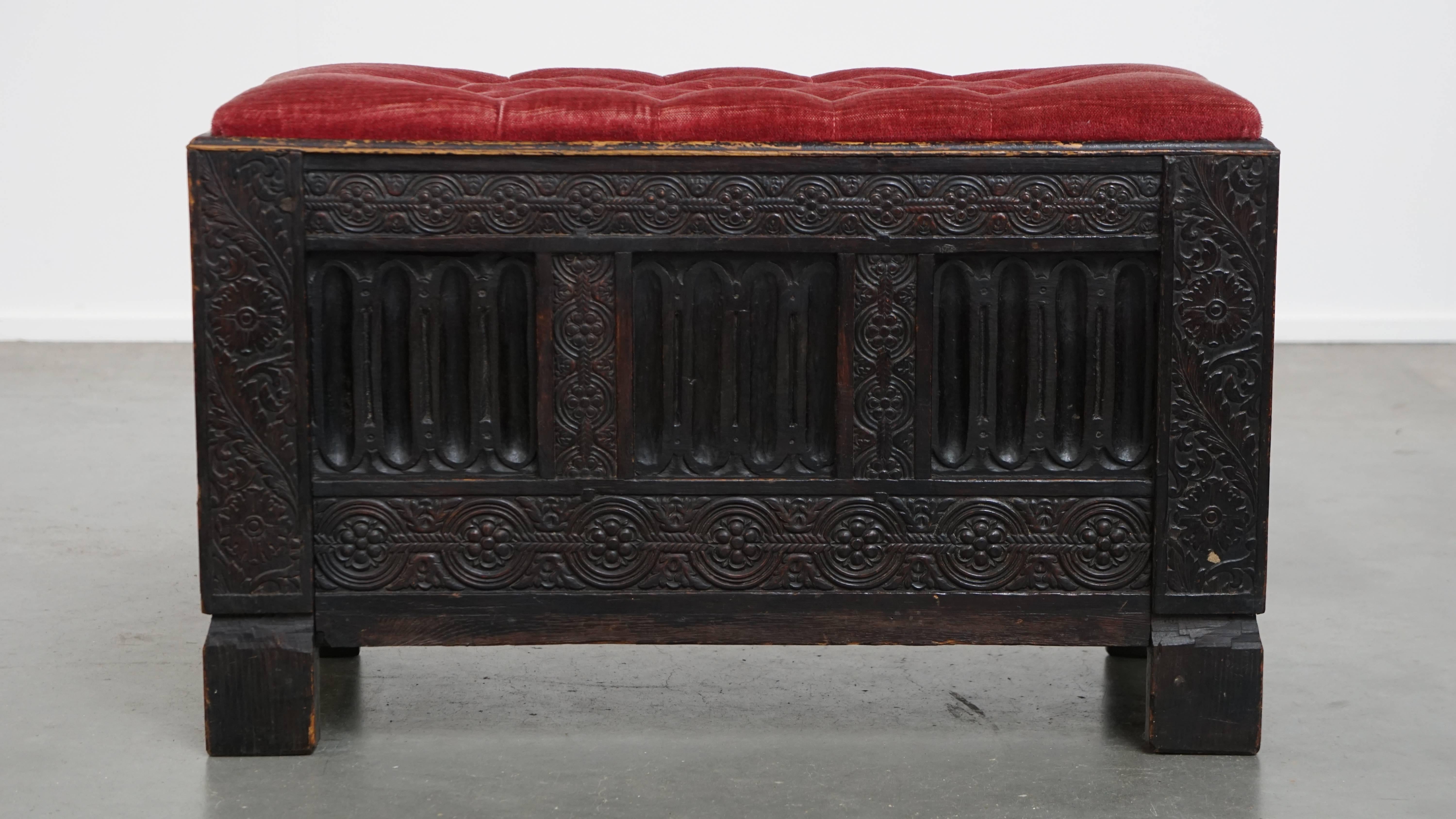 Offered here is this unique antique English bench/chest with beautiful wood carving and a red upholstered tufted seat.

This unique and very charming piece is incredibly versatile. It can be easily moved from one place to another as extra seating,