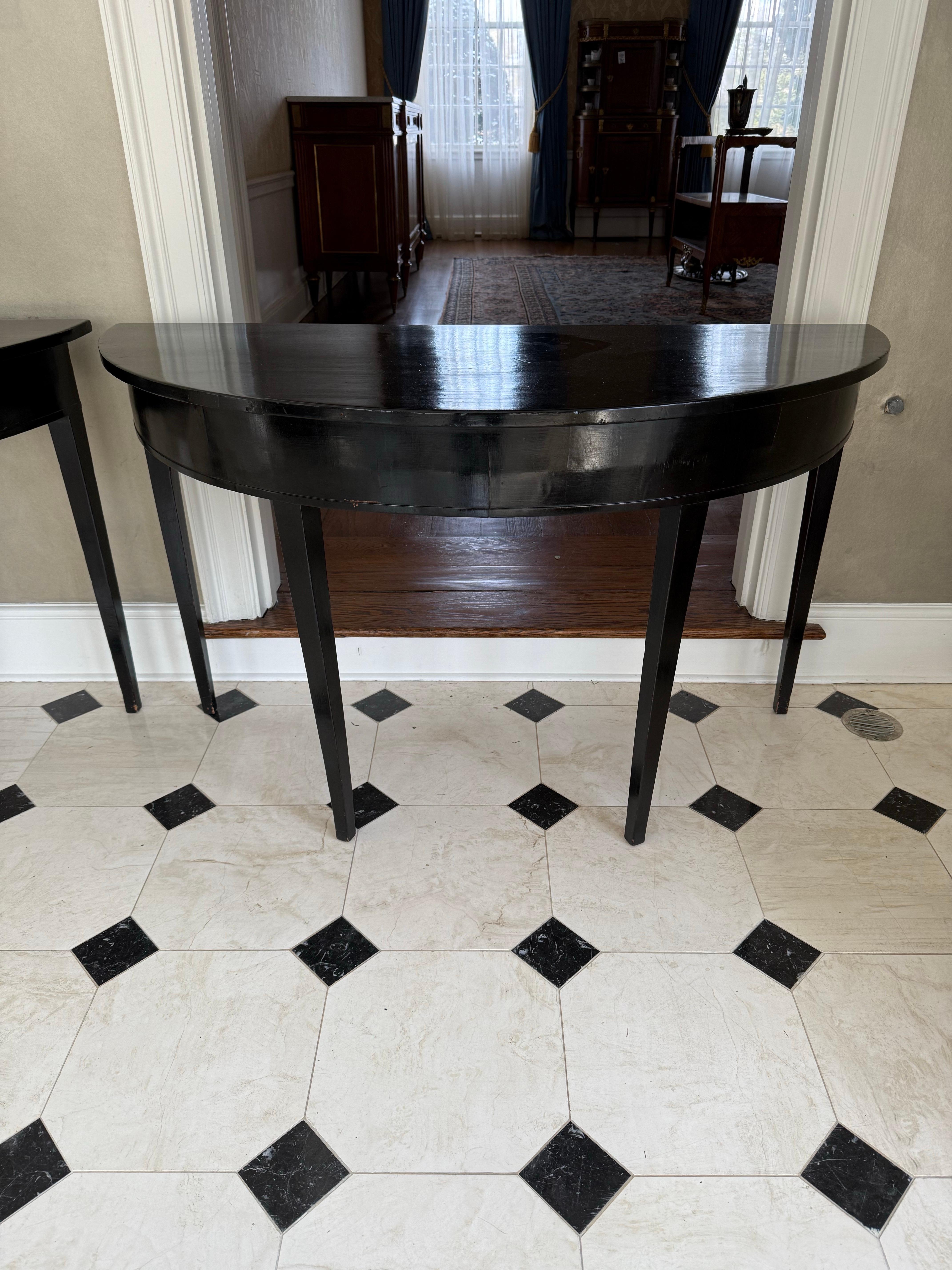 Antique English demilune console table in a black lacquered finish.  From an old church in London, circa late 19th century.  They do have age appropriate wear as shown.  Why not own the best?