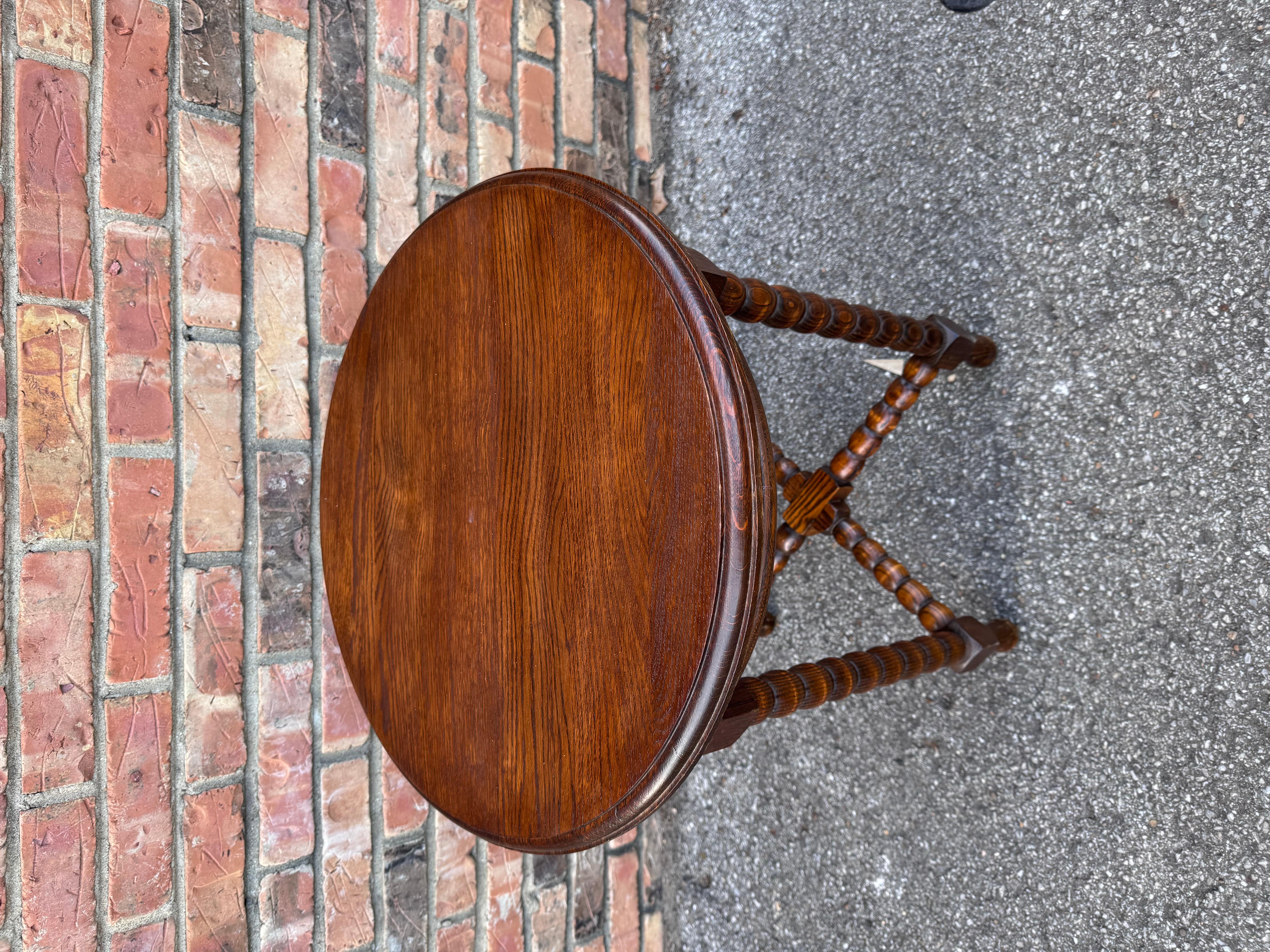 This is a beautiful Early 20th century English side table! This piece follows the traditional bobbin twist style. With Four legs and a matching stretcher. This would make a wonderful addition to a living room, office, or similar setting! This table