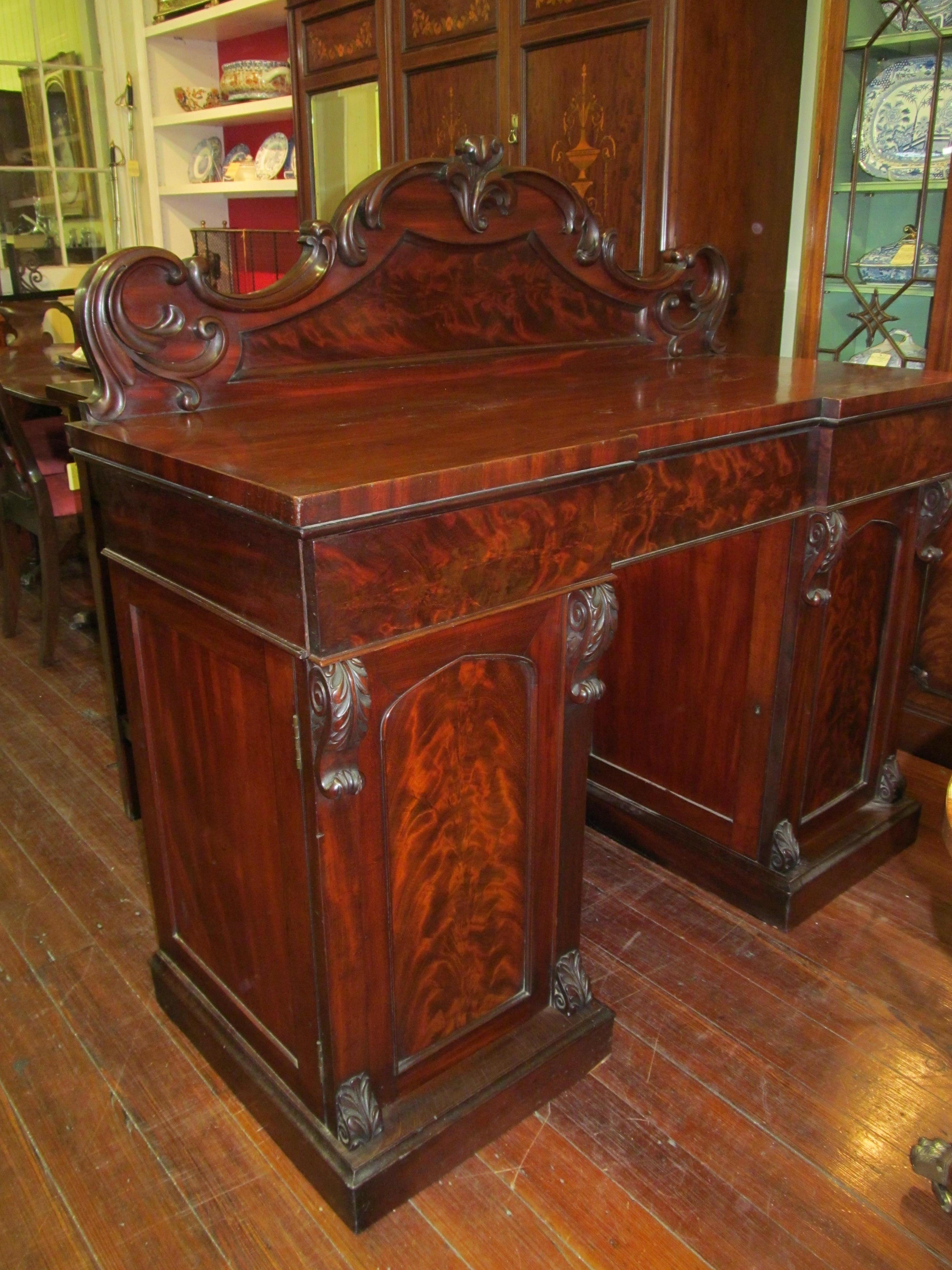 Fabulous quality antique English book-matched flame mahogany Victorian sideboard with pedestal cupboards, hand carved pilasters and interior cellarette drawer (right side).

Please note superb book-matched flame mahogany and cellarette drawer behind