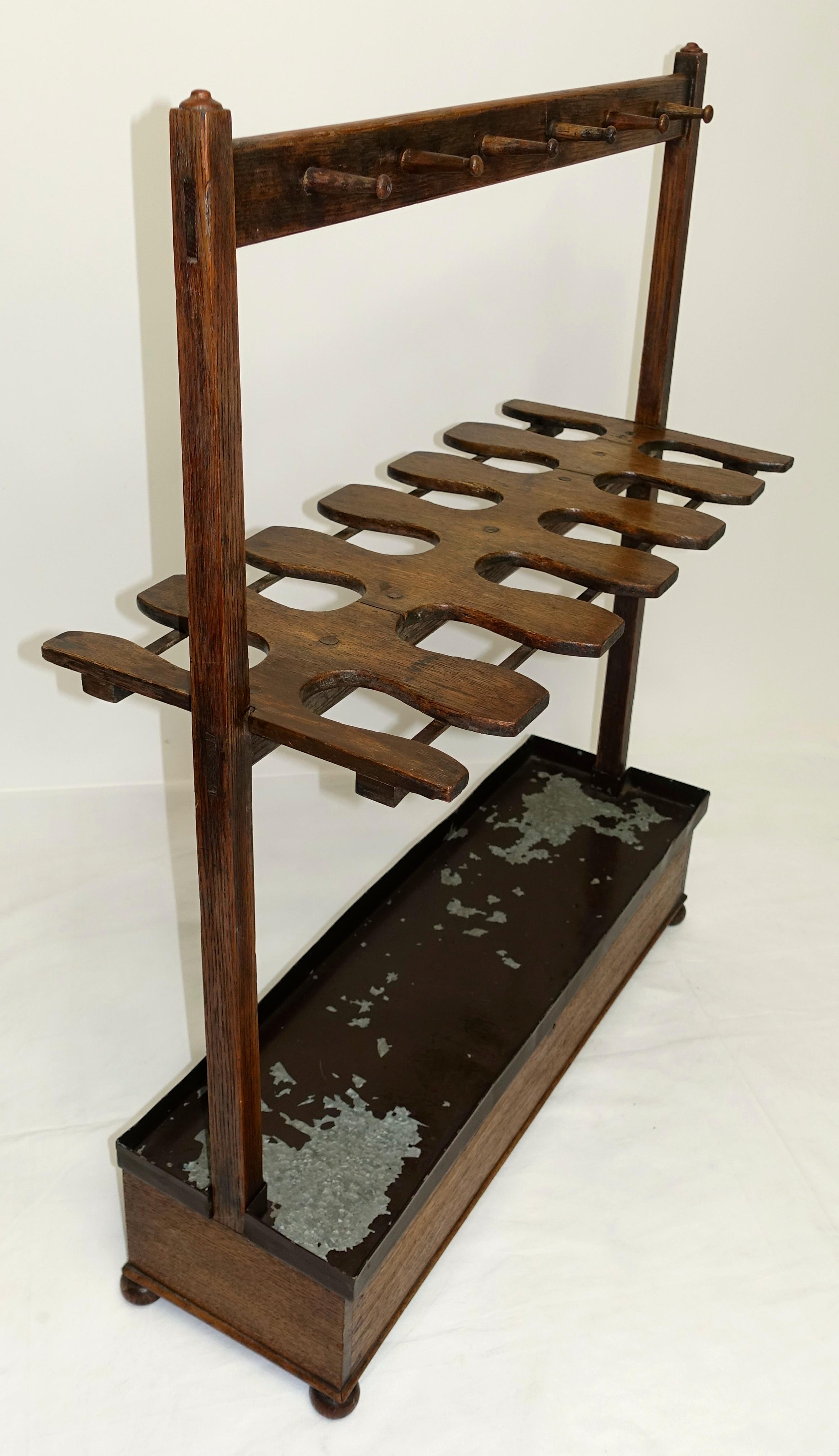 Late Georgian six pair boot rack made of English oak wood. Functional form with through mortise and tenon construction, and upright standards topped with small turned buttons. 12 pegs hold crops, whips and leather laces. The dovetailed top hinged