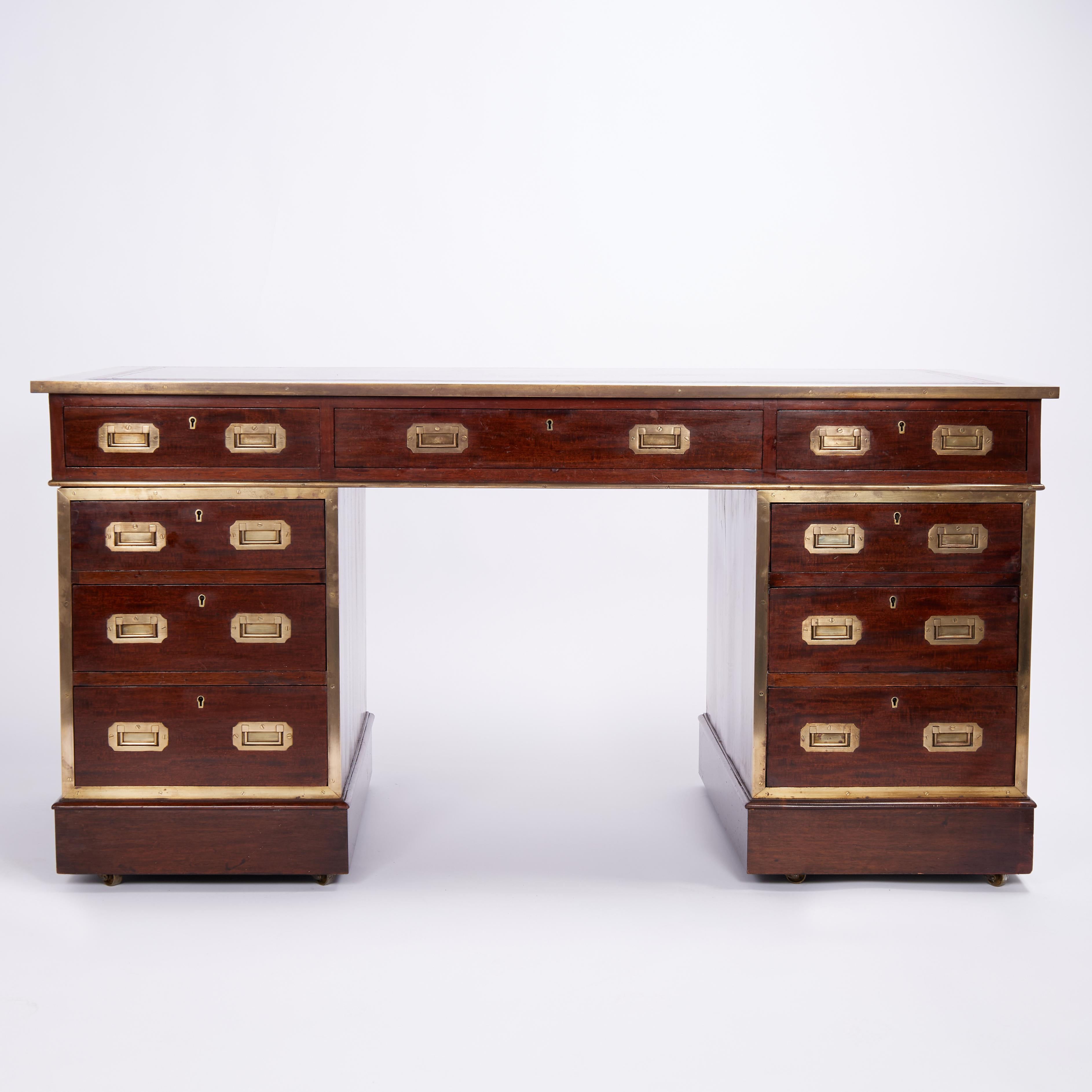 Handsome 19th century English campaign desk handcrafted in mahogany in three piece construction featuring the original tooled leather top on a case with three drawers on two pedestals with three drawers each, campaign brass hardware, and classic