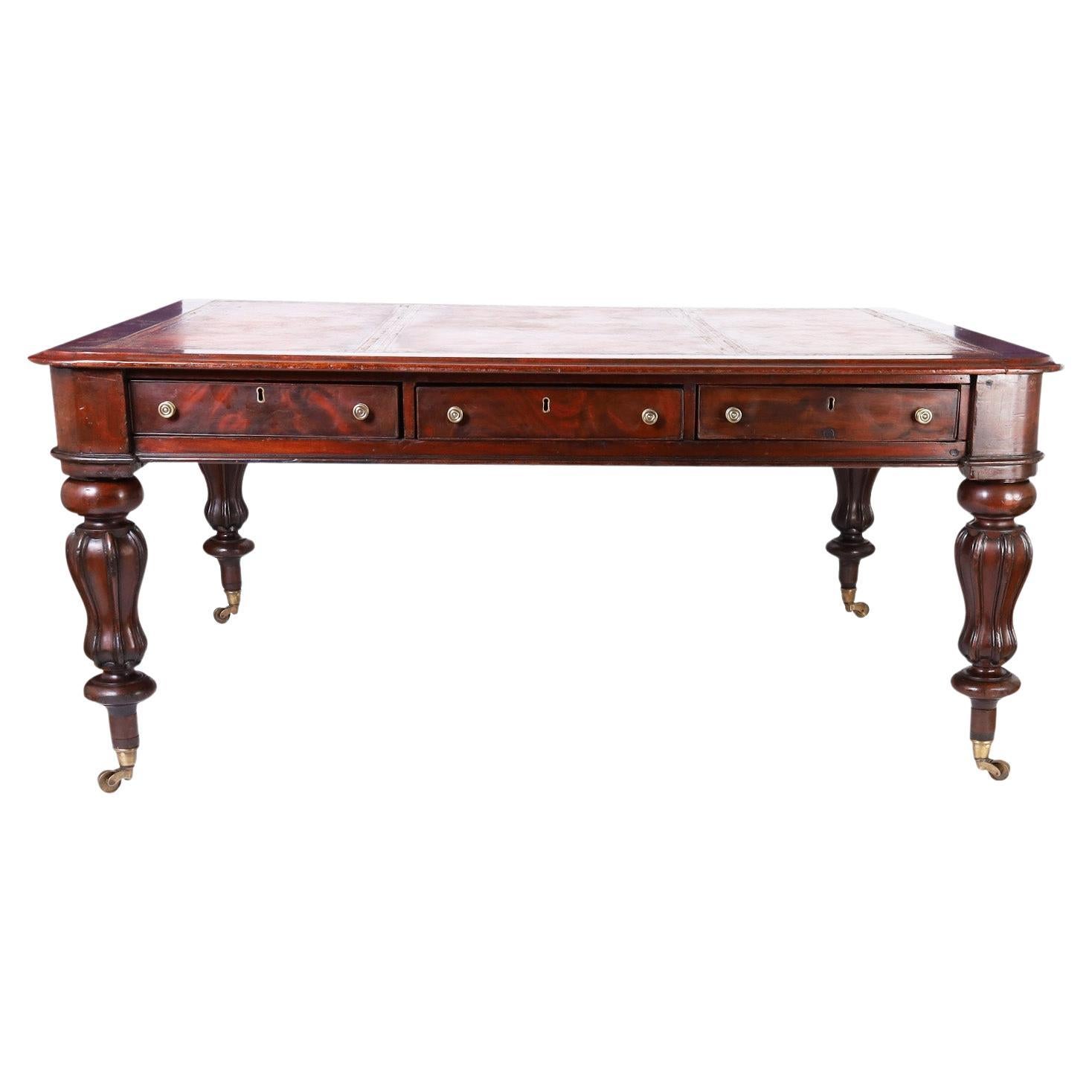 Impressive 19th century English partners desk, regency in style, crafted in mahogany having a tooled leather top on a case with three drawers on each side supported by dramatic turned and beaded legs on brass casters.
