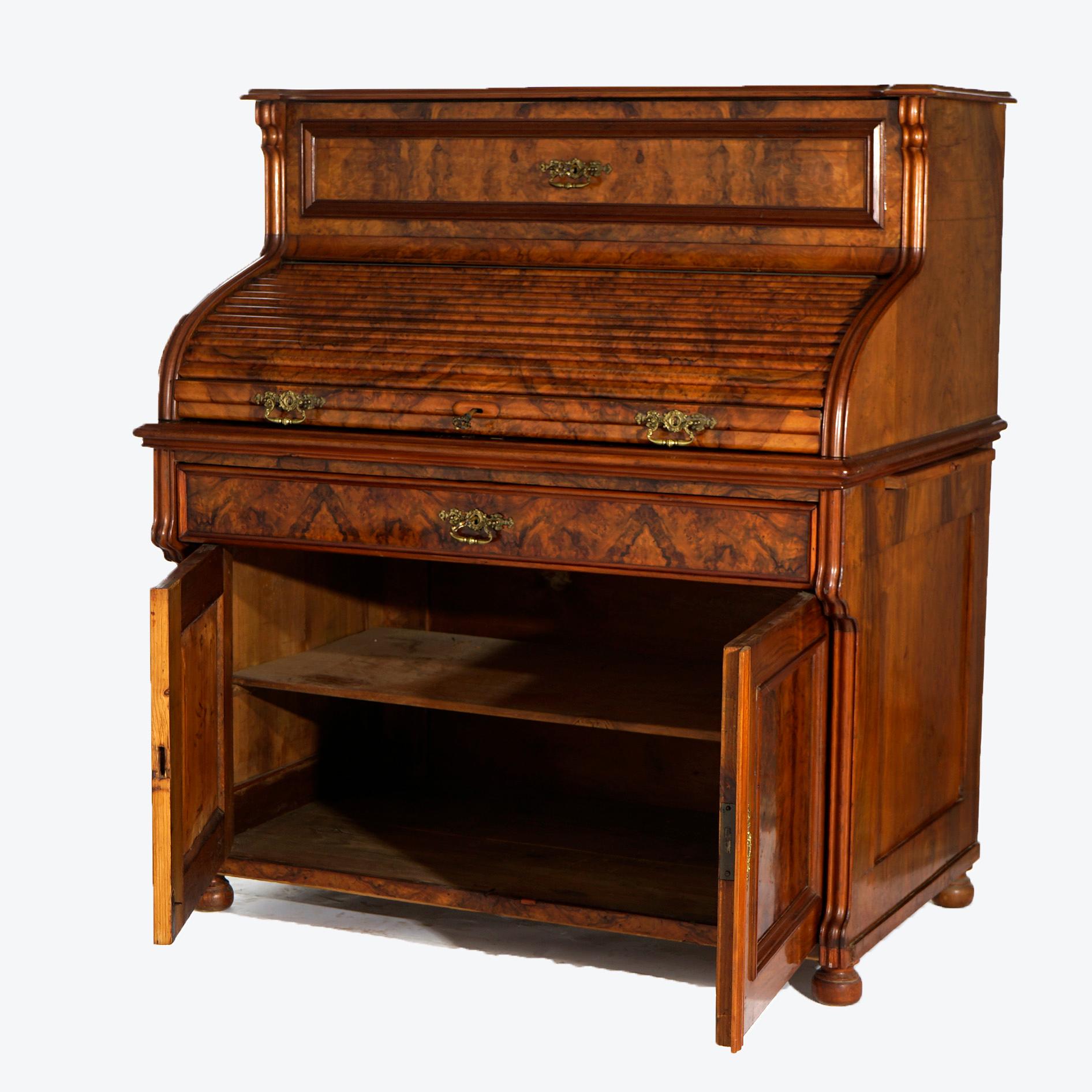 An antique English ladies desk offers burled walnut and mahogany construction with roll top opening to writing surface and storage compartments over lower cabinet raised on bun feet, c1890

Measures- 50.5''H x 44.5''W x 29''D.

Catalogue Note: Ask