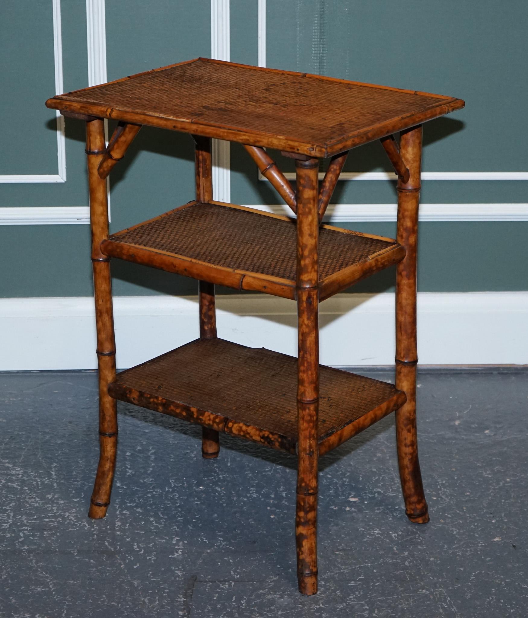 We are excited to present this stunning antique burnt bamboo side end lamp table.

The table is raised on flared legs and with three shelves.
All shelves are made of tightly woven rush.

We have deep cleaned, hand waxed and hand polished