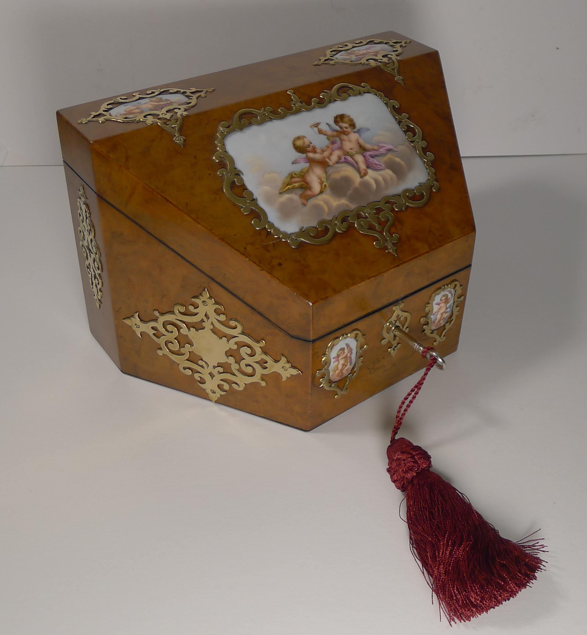 A quite wonderful and romantic stationery box, ready to grace the finest of desk-tops.

Made from burr walnut the wedge shaped box is smothered in fine quality polished brass mounts and five fabulous hand painted porcelain plaques, all without