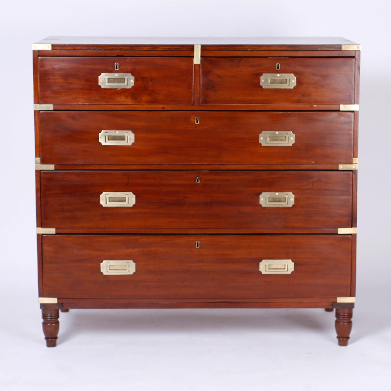 Antique British colonial 19th century English five-drawer chest handcrafted in well grained mahogany with the original brass hardware and Classic turned feet.