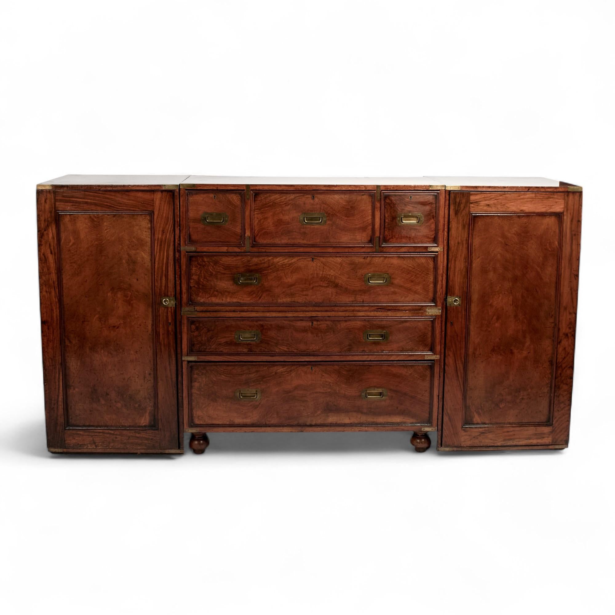 Rare and remarkable 19th Century British Colonial campaign chest handcrafted in mahogany and rosewood with six drawers and turned feet on the center chest and two attached side cabinets all with the original brass hardware. Perfect for an English
