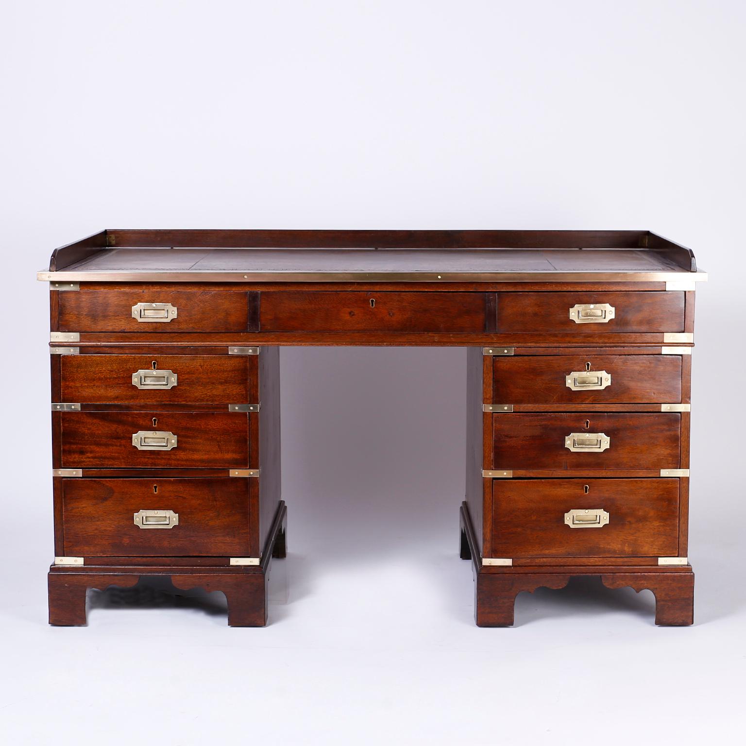 Handsome Chippendale style Campaign desk with a gallery around the top which retains its original tooled leather now aged to perfection. The seven drawer case is mahogany and has brass Campaign hardware, a finished back and sits on bracket feet.