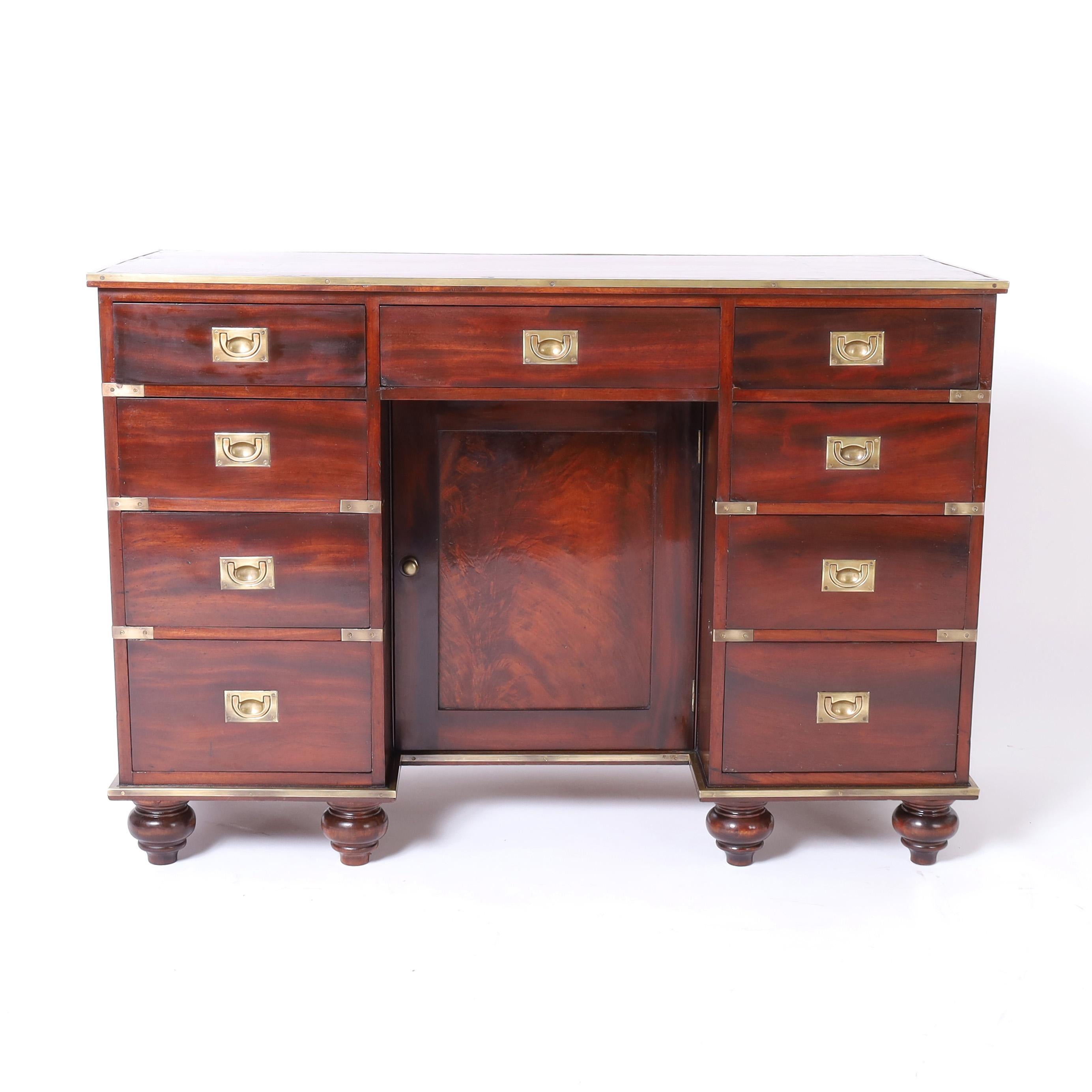Hermoso escritorio colonial británico antiguo Elaborado en caoba en forma de campaña con la parte superior de cuero rojo original, nueve cajones en el frente con un gabinete único de rodillas, herrajes de latón y pies torneados. Pulido francés a la