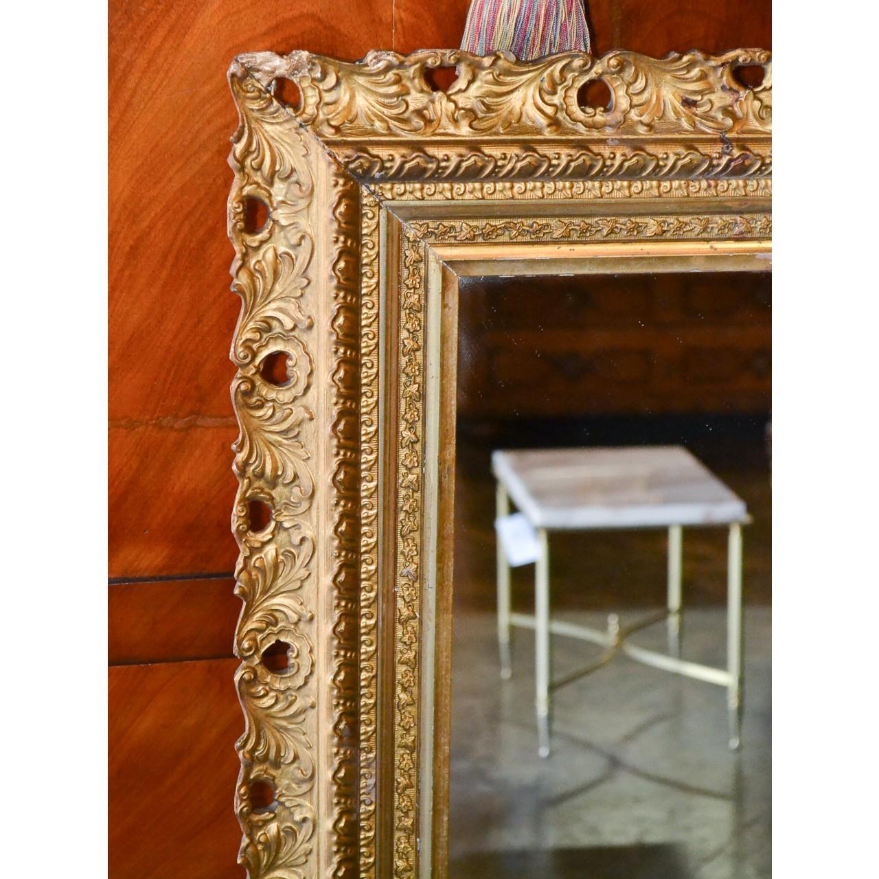 Charming antique English carved giltwood wall or console mirror. The outer border carved in relief with scrolling acanthus leaves. The inner border carved in a laurel leaf motif,

circa 1900.