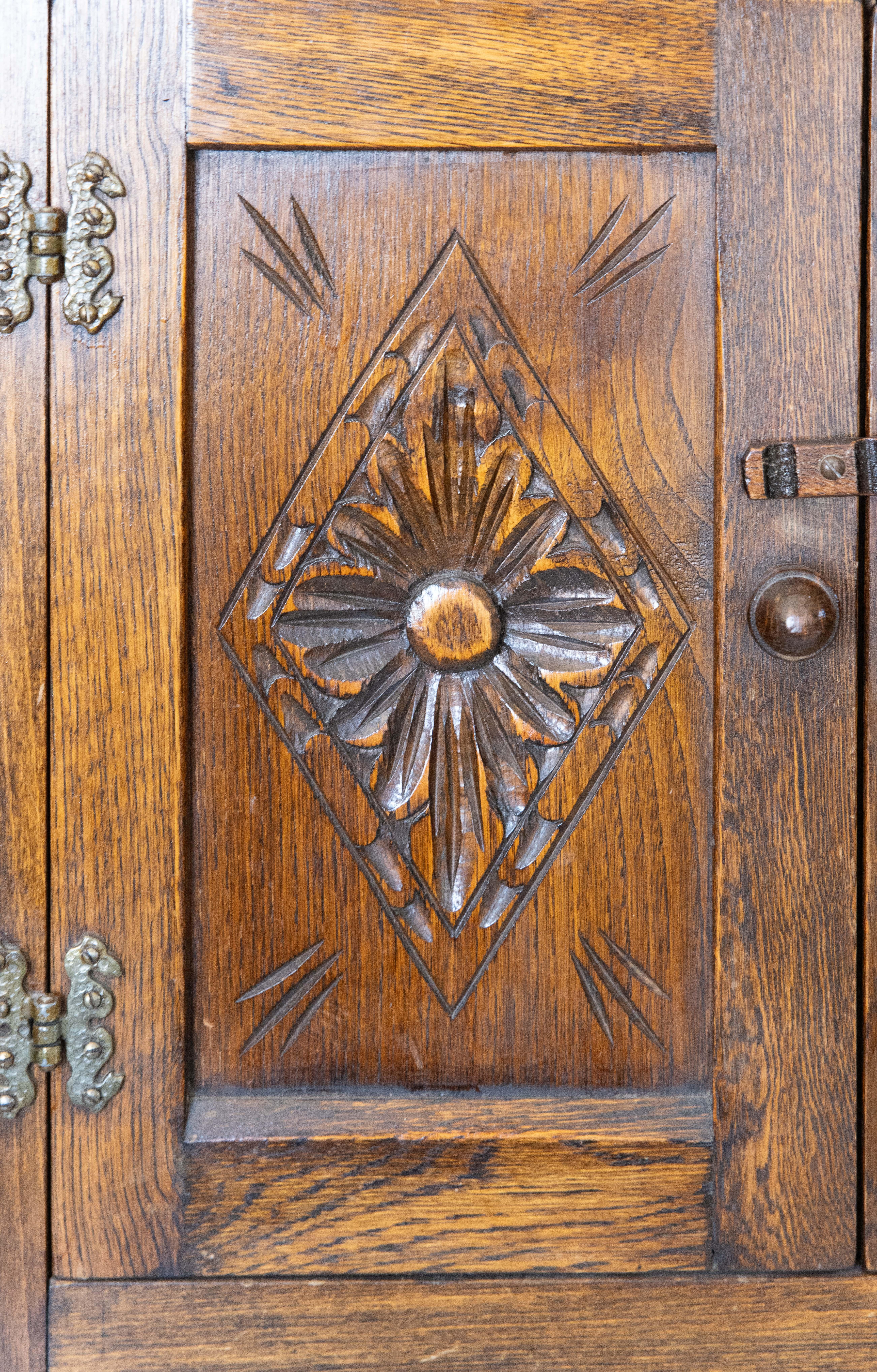 Ancienne armoire naine en chêne sculpté de style anglais du 17e siècle. La construction à panneaux est entourée d'une paire de portes, de boutons à glands, de charnières d'époque et d'une belle patine.