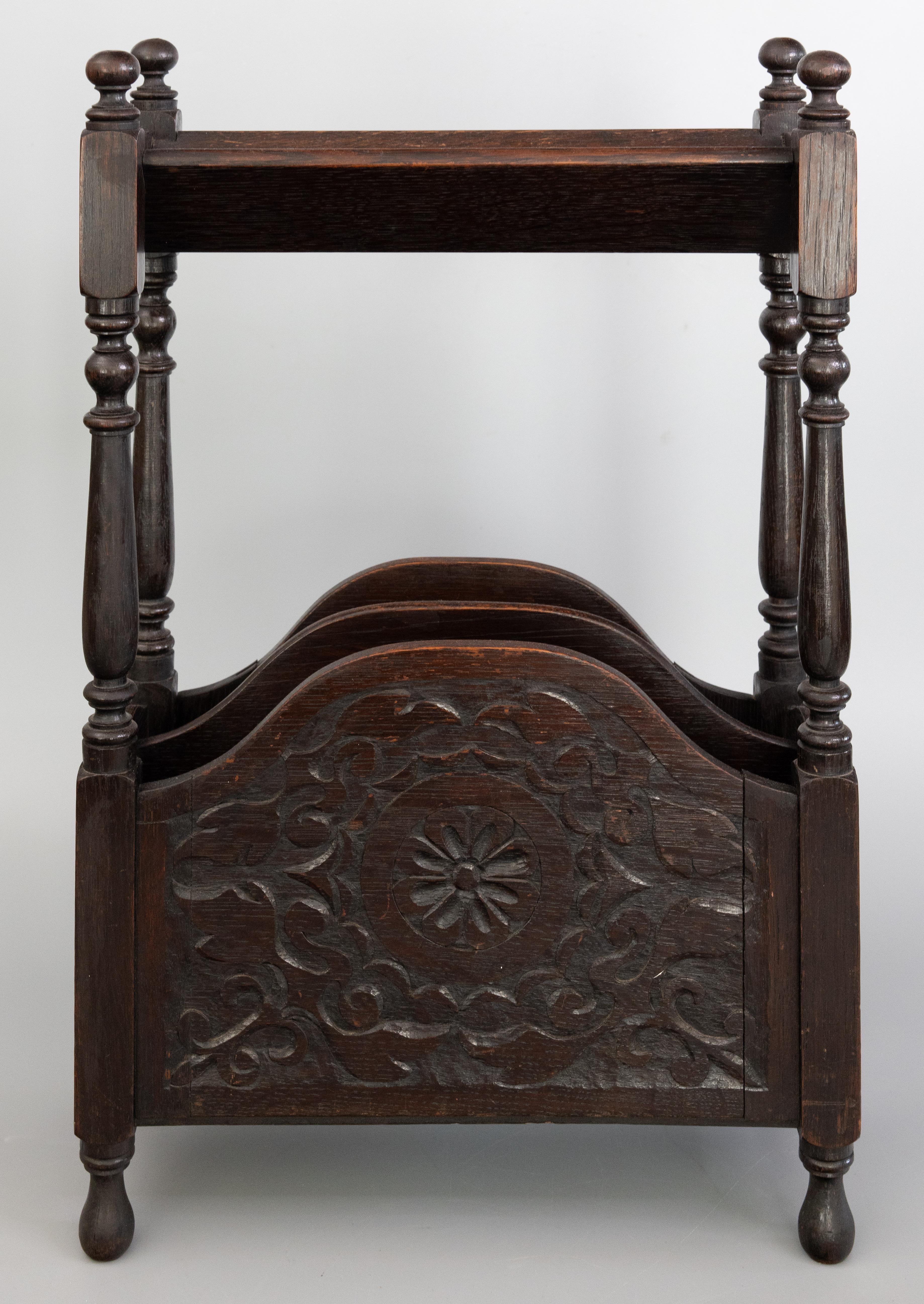 A superb antique English Edwardian hand crafted oak book trough and magazine rack stand, circa 1910. This fine stand has hand turned legs and hand carved floral and scroll designs in a lovely patina. It's perfect for storing magazines and books in a