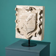 Antigua placa inglesa con escudo de armas de piedra tallada sobre peana
