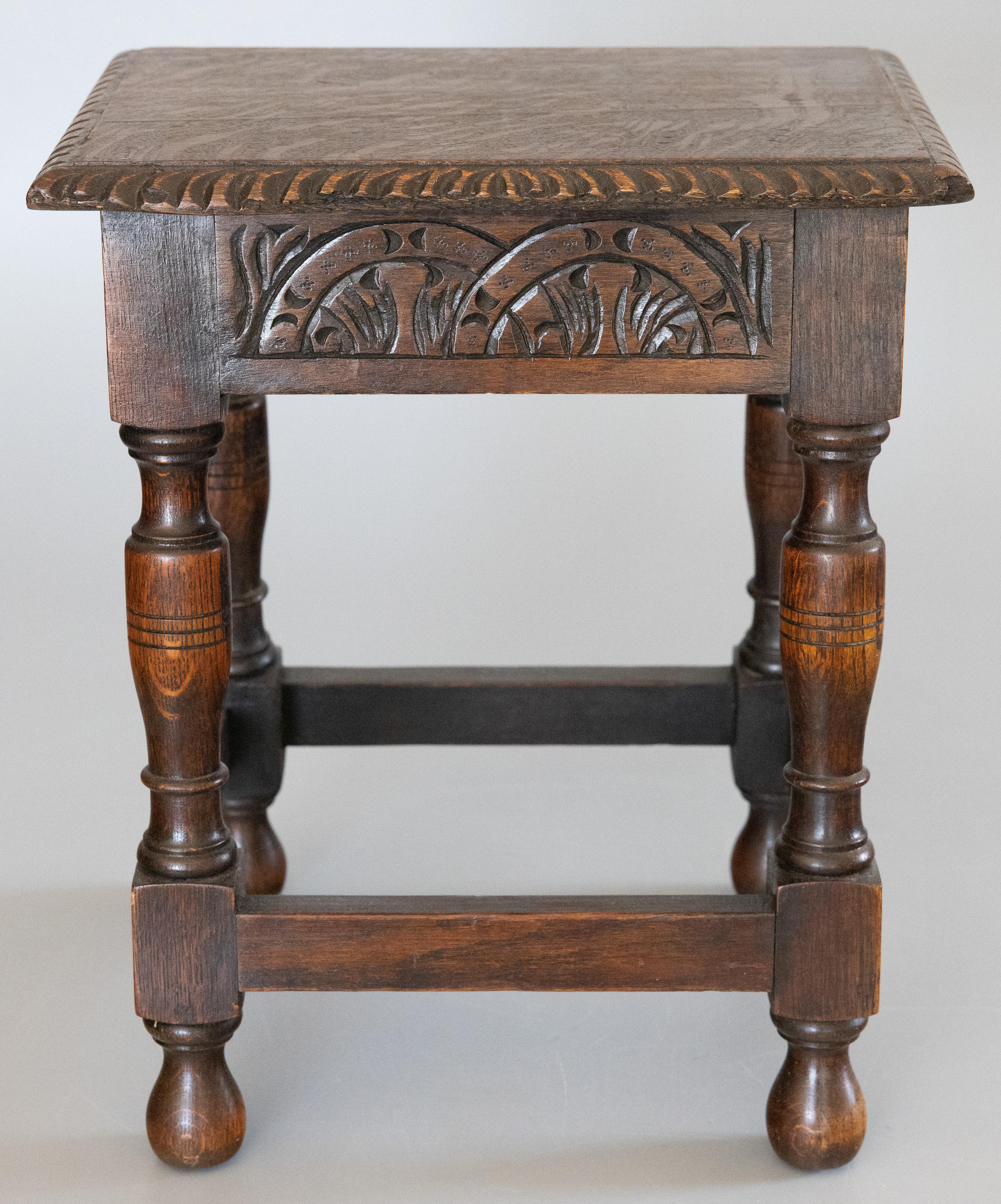 A superb antique early 20th-Century English oak joint stool with a beautifully carved apron, hand turned legs, and lovely figured tiger oak seat with scalloped edges. This fine stool would be great for extra seating and also perfect as a side table
