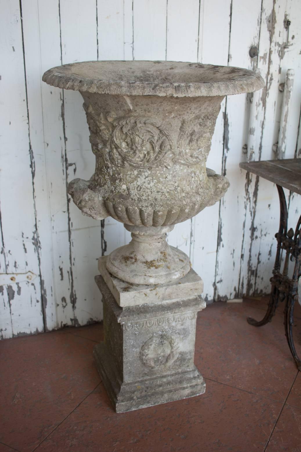 Antique carved sandstone semi gadrooned urn on plinth with carved head detail.