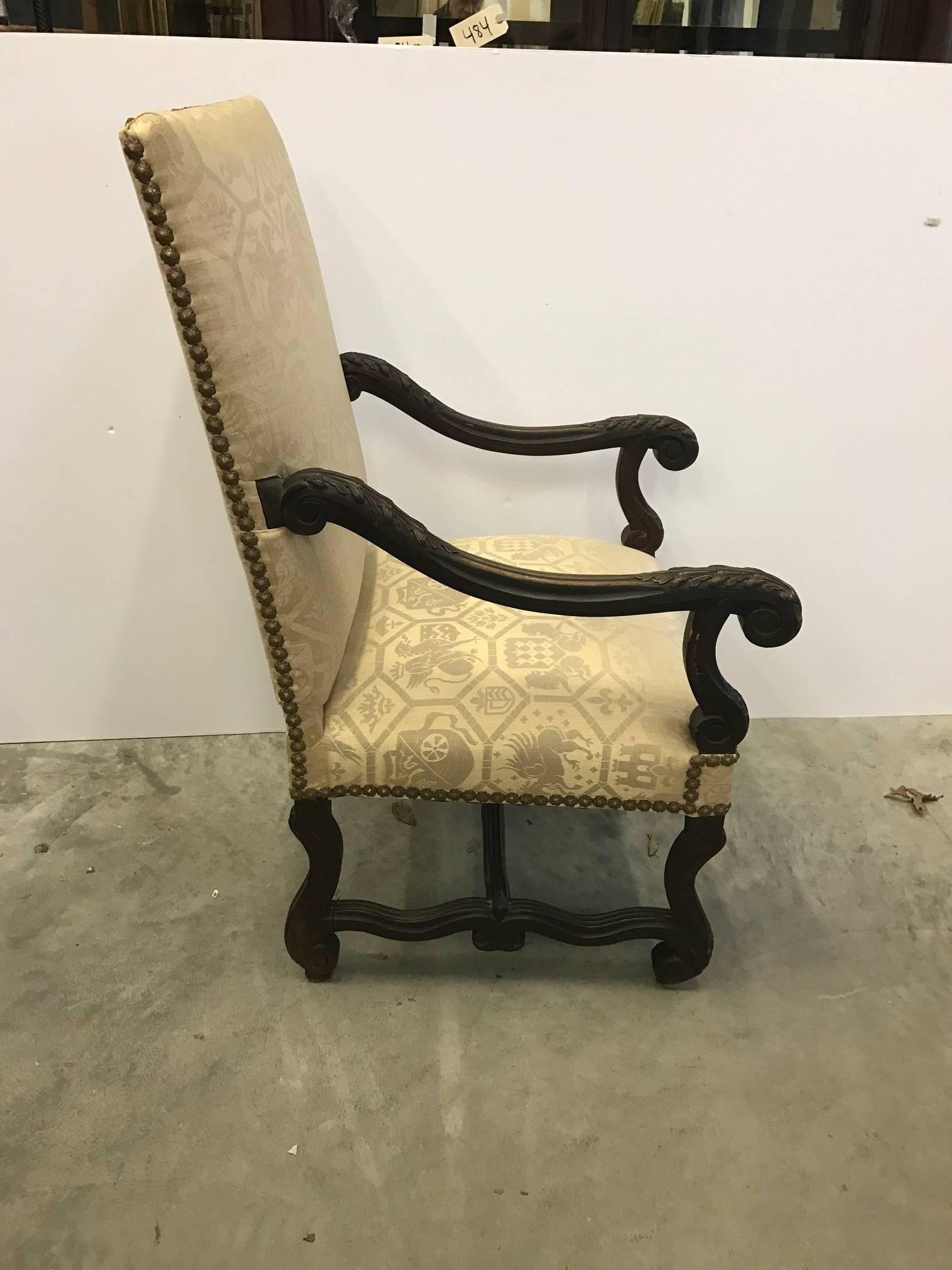 A 19th century hand carved English library chair. Long sloping arms with acanthus leaf carving. New soft yellow damask upholstery. Stately and handsome statement chair.