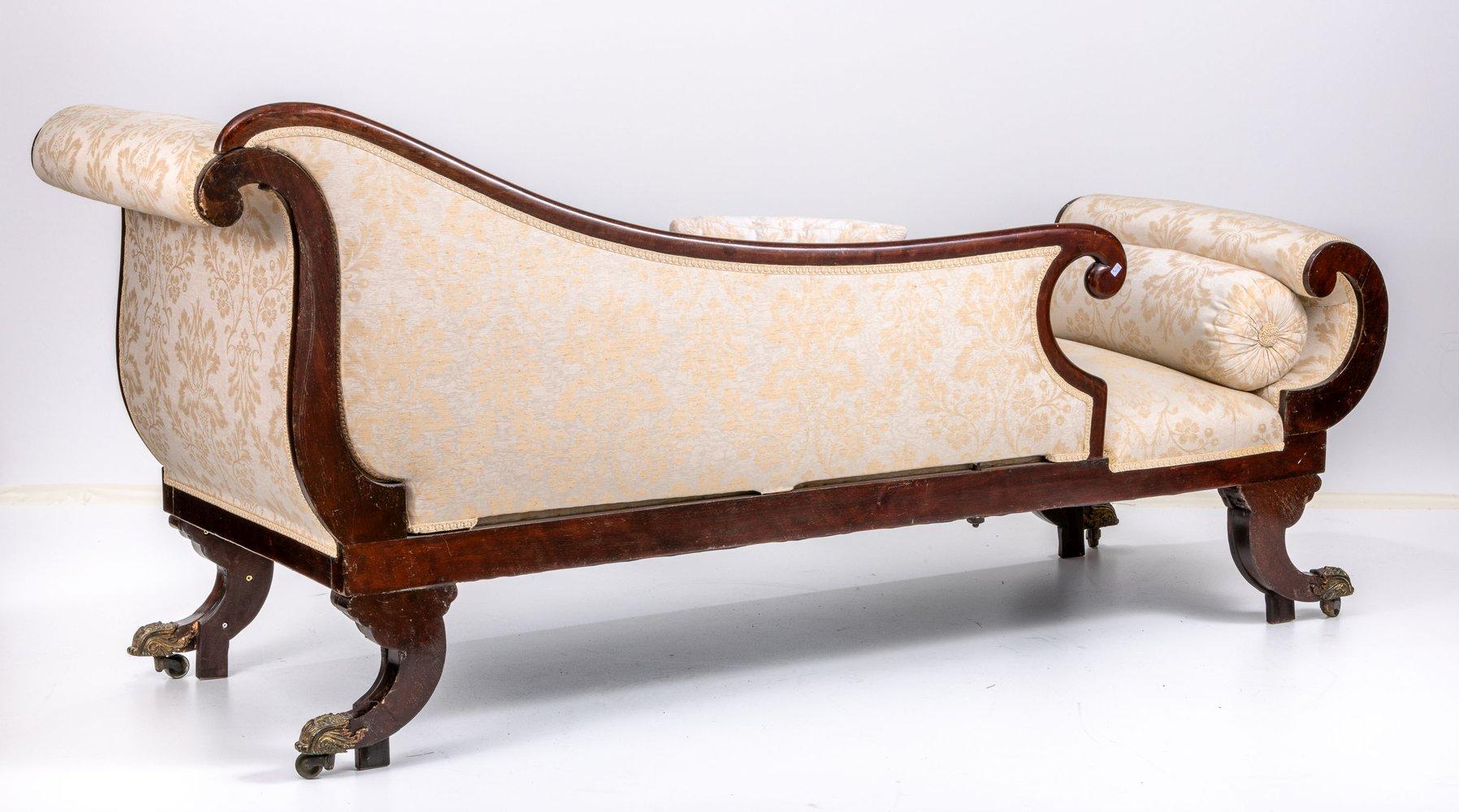 Antique English Chaise Longue/ Recamiere, Mahogany, arround 1830

Mahogany with Boulle decor. Tub shape, upholstered. Curved backrest tapering to one side with volute end. Godroned and voluted saber legs with brass shoes and castors. Two pillow