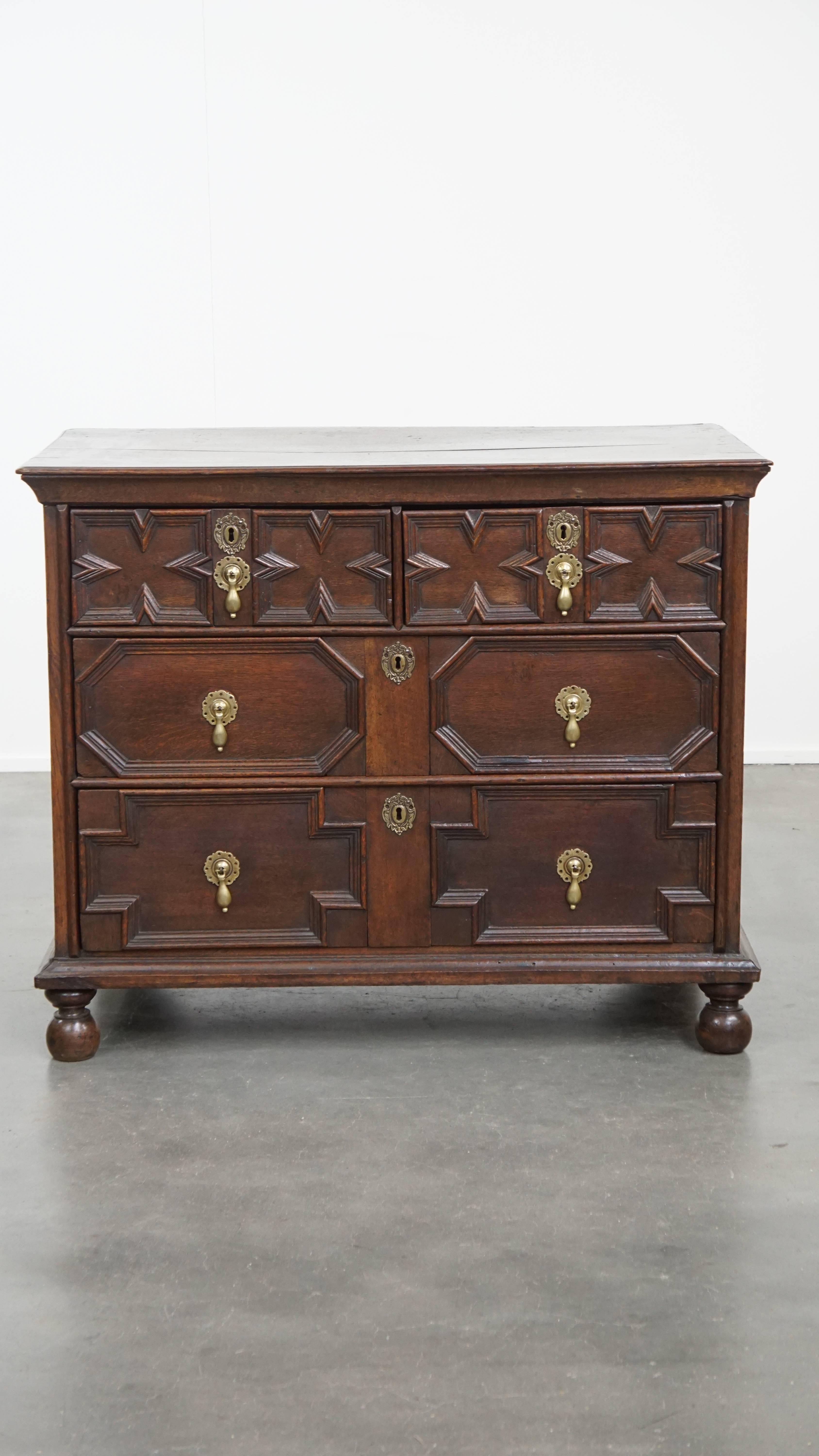 Offered is this charming antique English chest of drawers from the 18th century, featuring unique paneling and original bun feet. This beautiful antique oak chest of drawers is undoubtedly a true eye-catcher!

This English chest dates from the mid