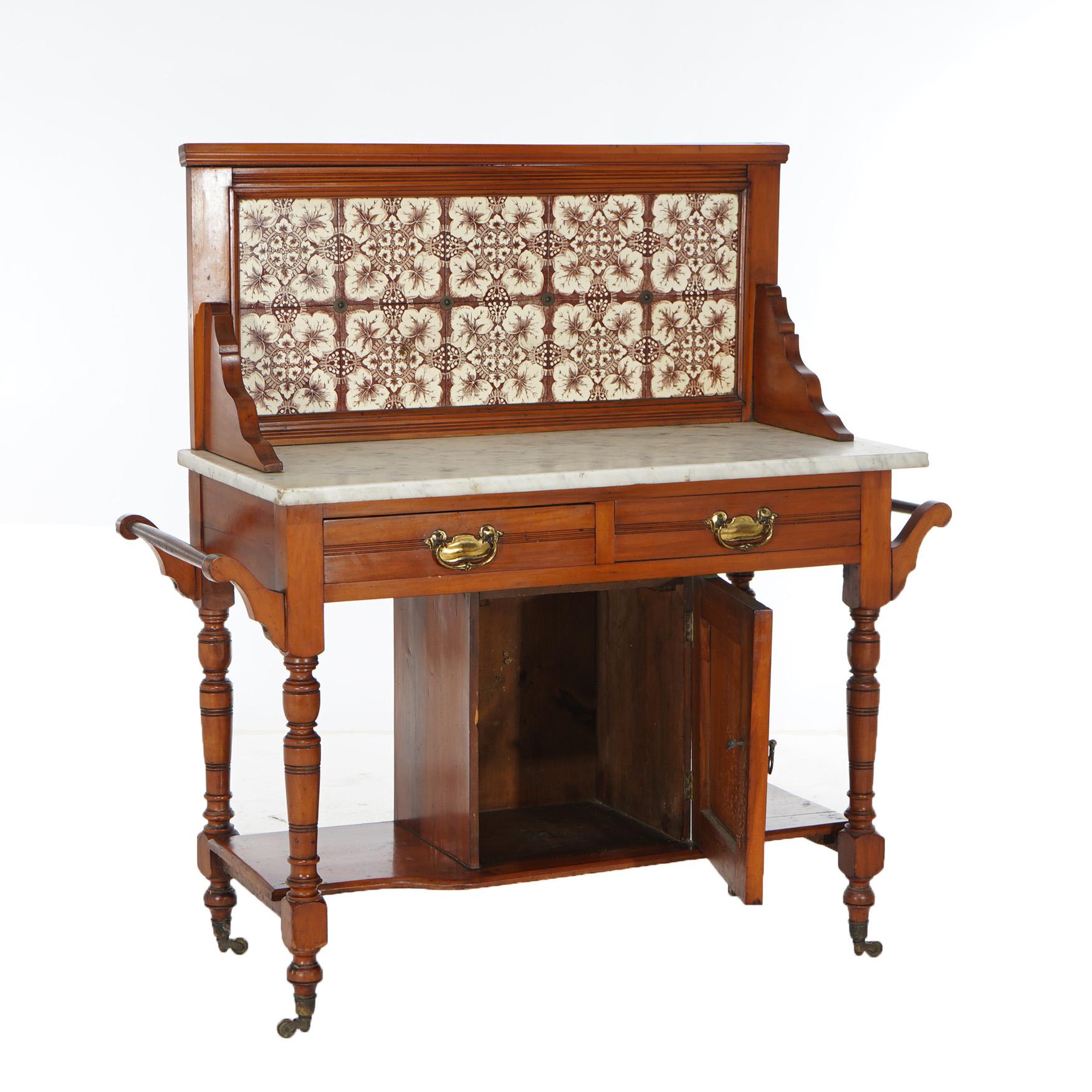 An antique English wash stand or dry sink offers chestnut construction with tile backsplash over marble top case having double doors opening to blind storage compartment, lower central cabinet, and raised on turned legs with casters,