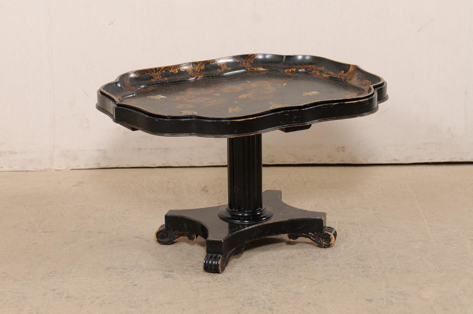 A 19th century English chinoiserie tray top on carved pedestal coffee table base. This coffee table from England has an antique tray top, with beautifully scalloped edges, black in color, with a bronze/gold and mother of pearl inlaid top decorated