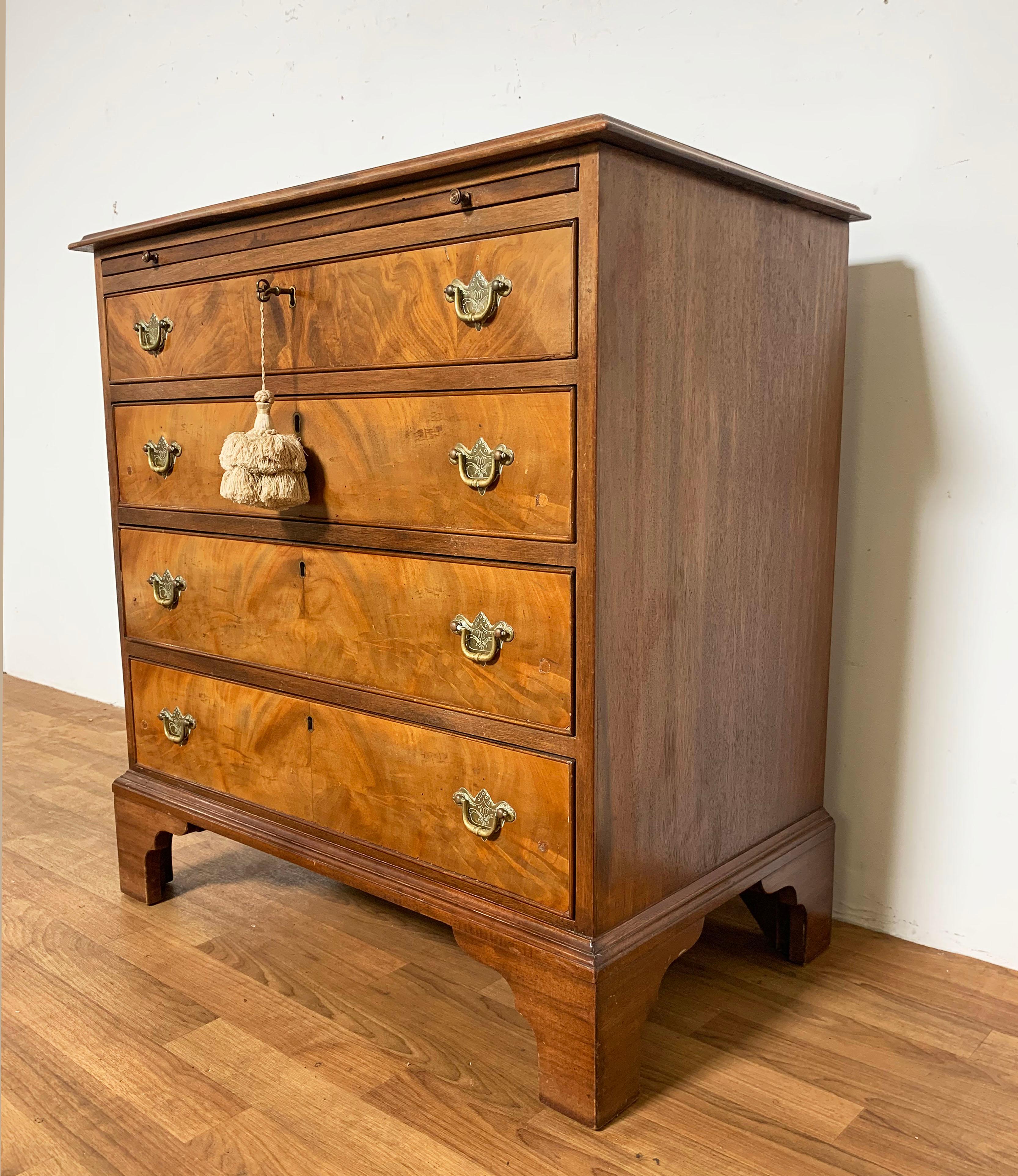 An English Chippendale chest of four drawers circa late 18th century. Mahogany, with dressing slide and mounted on bracket feet. Original brasses. Working key in top drawer, currently fitted with felt insert for storage of silver cutlery.