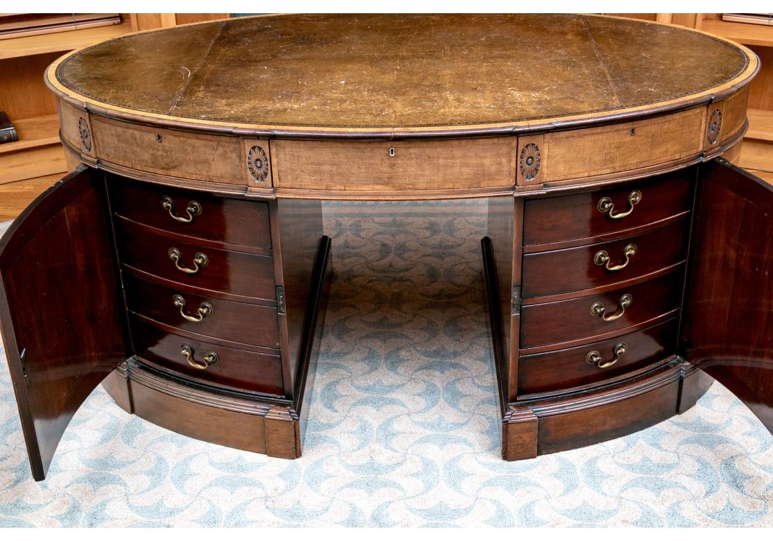 Un exquis bureau d'associé anglais de style Chippendale vers 1860 en acajou brun moyen avec des incrustations de bois de satin brun clair aux tons chauds. Le bureau présente un profil ovale unique avec un plateau en cuir brun incrusté et estampé