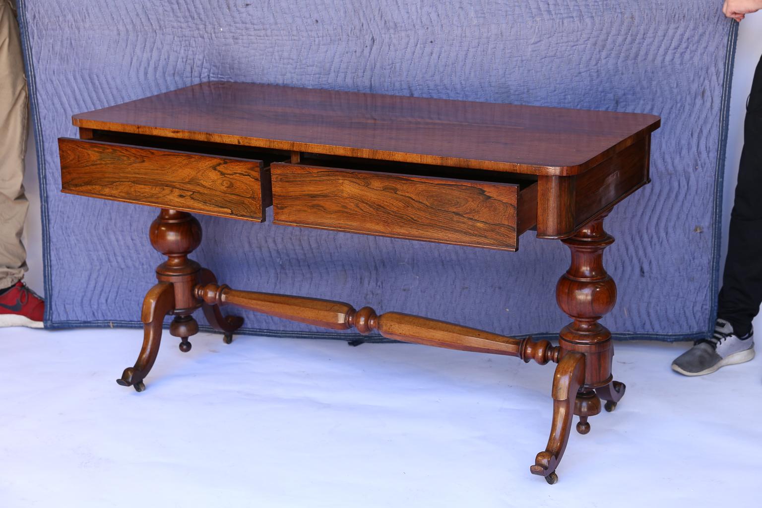 Found in England, this is a beautiful 19th century console table. The two drawers on the front are almost hidden as they blend with the construction of the table. The piece stands on four iron and brass casters attached to the feet of two turned