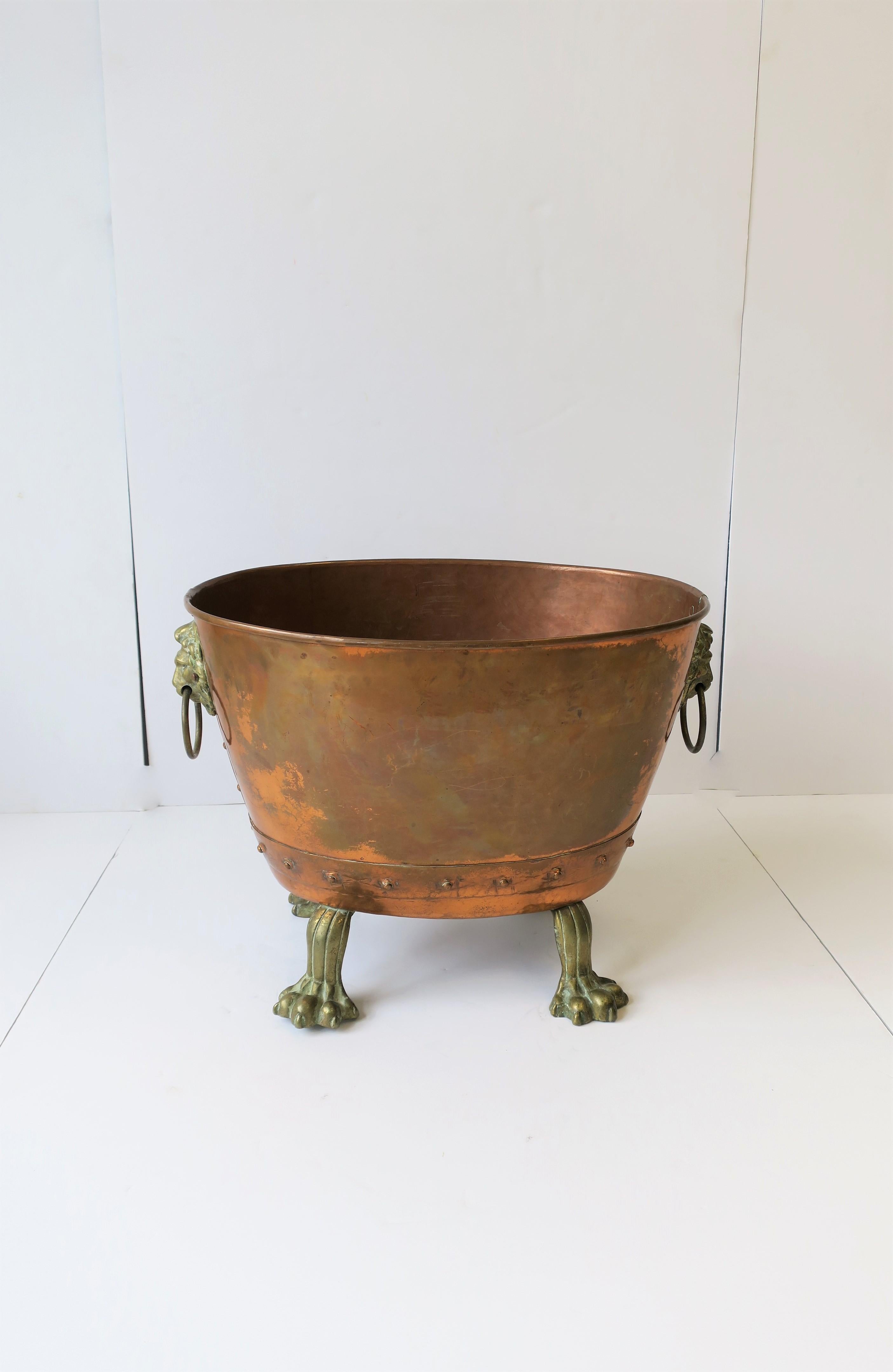 A beautiful and substantial turn-of-the-century English Lion head and paw feet copper and bronze/brass oval pot. Detailed lion heads on either side with ring handles, four paw feet, and rivets along base. Hand-hammered, England, circa early 20th