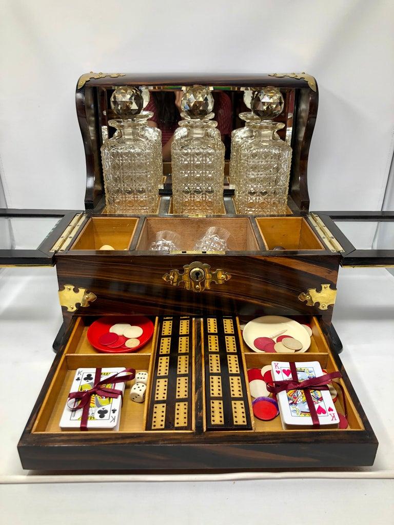 Antique English coromandel wood games box tantalus fully fitted with games pieces and crystalware.