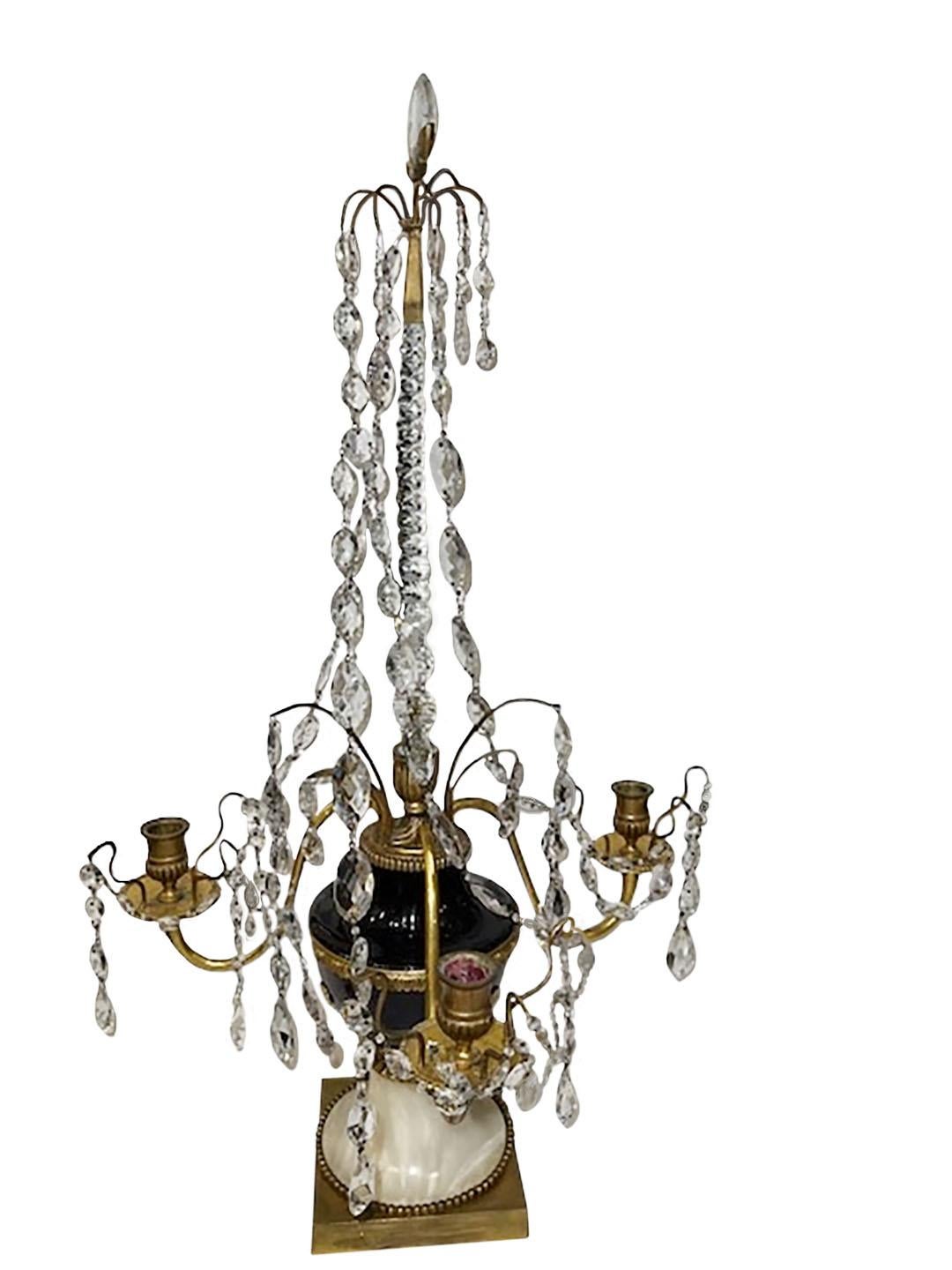 A pair of Russian gilt bronze three candle arms with amethyst and clear cut glass prisms, beads and pear shaped drops in the form of a baluster vase. On a white marble plinth. Attributed to Johann Zech, late 18th century.