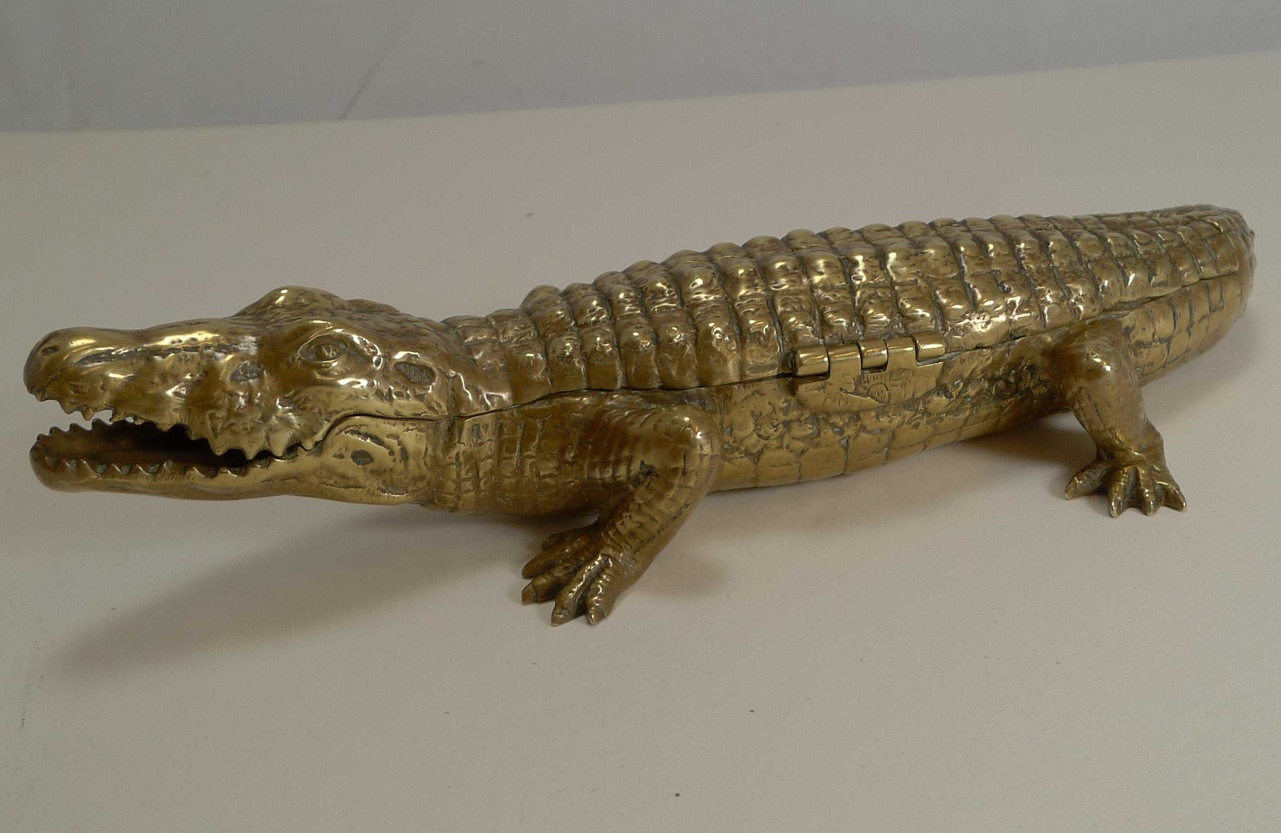 A truly magnificent and scarce novelty inkwell, cast in the form of a Crocodile / Alligator, in heavy solid brass.

The hinged lid to the centre lifts to reveal a central section with two original removable ceramic ink chambers. Either side of