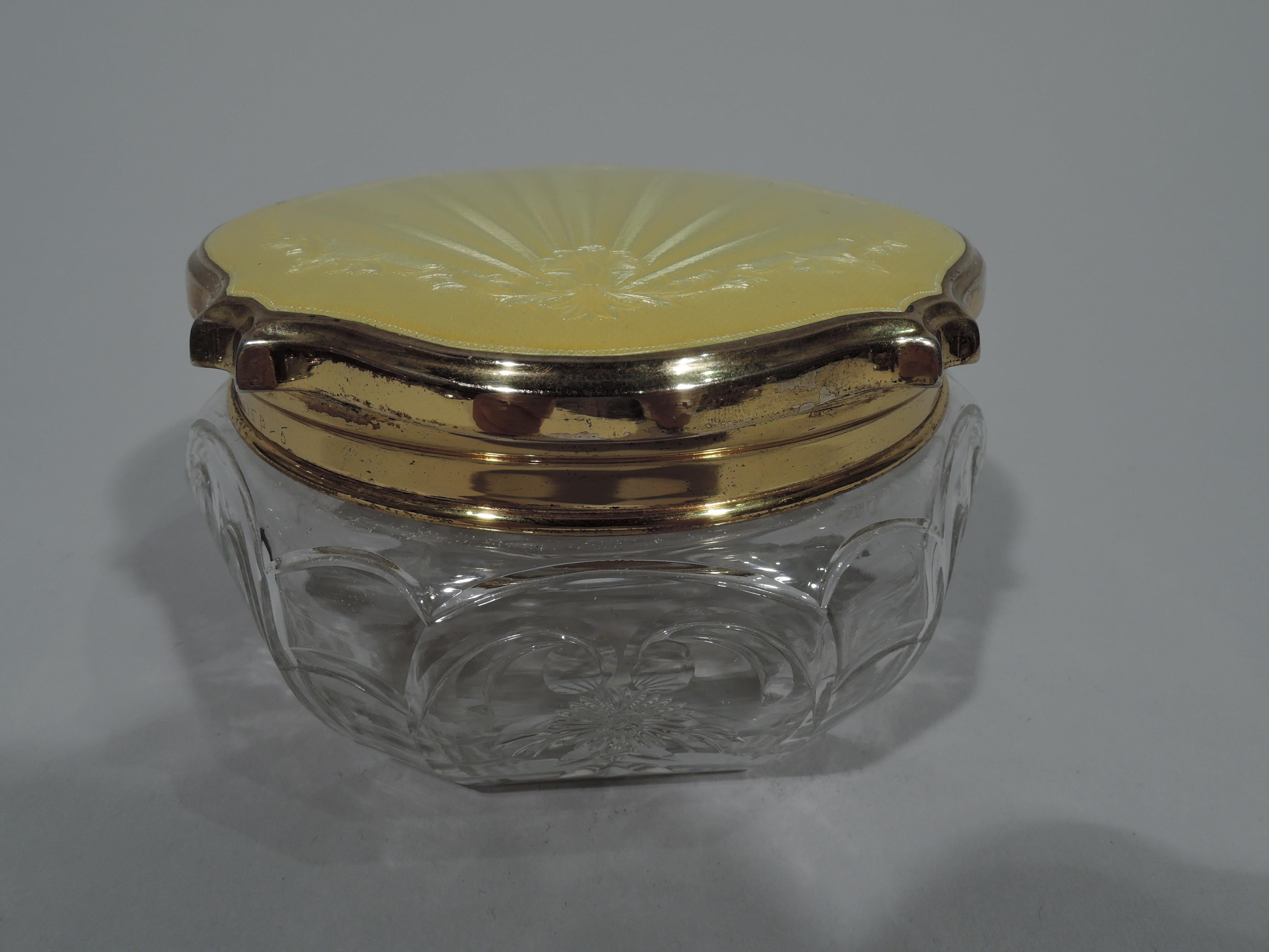 George V crystal powder jar with gilt sterling silver and enamel cover. Made by Adie Brothers in Birmingham in 1930. Bellied with alternating wide and clear facets and stylized floral ornament. Gilt sterling silver shaped cover has gently curved top